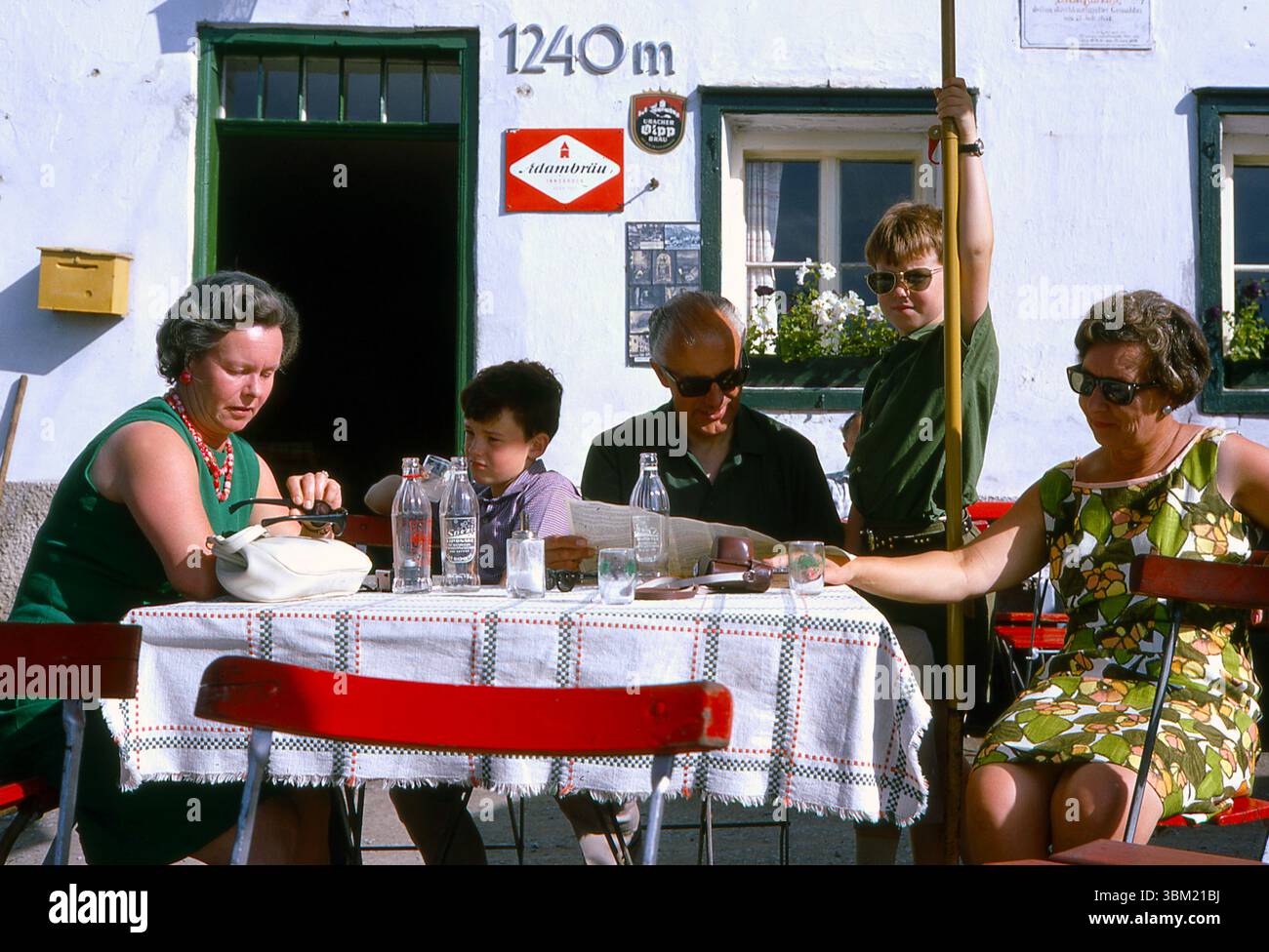 Années 1960 Autriche - Un groupe familial de touristes assis devant une brasserie ou une maison d'hôtes près d'Innsbruck, buvant de la limonade Spezi en 1967 - il y a des panneaux de bière pour Adambrau et Uracher Olpp Bräu Banque D'Images