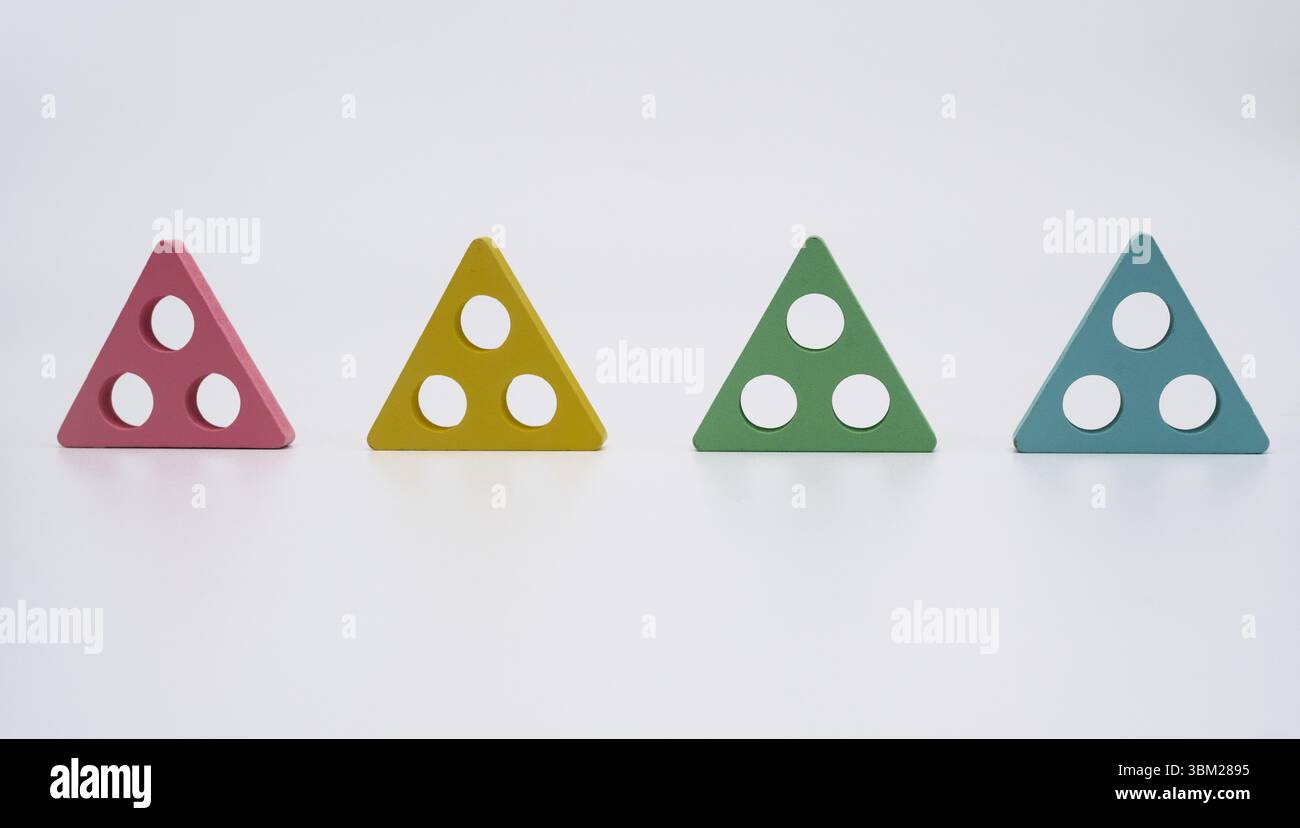 composition avec des formes triangulaires vibrantes symbolisant l'ordre et la structure. Quatre triangles géométriques colorés avec des trous circulaires placés en rangée sur blanc Banque D'Images