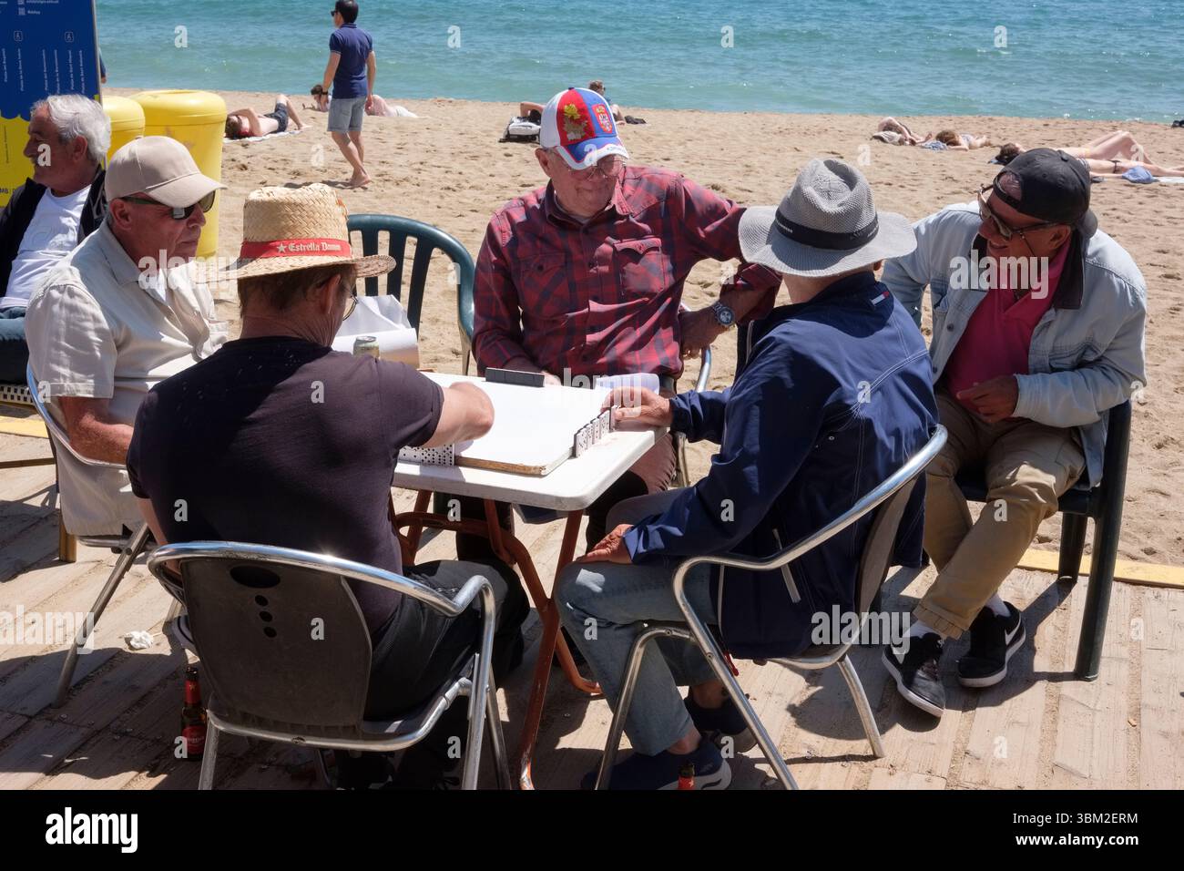 Hommes jouant aux dominos le long de la plage de nova icaria, Barcelone, Espagne. Banque D'Images
