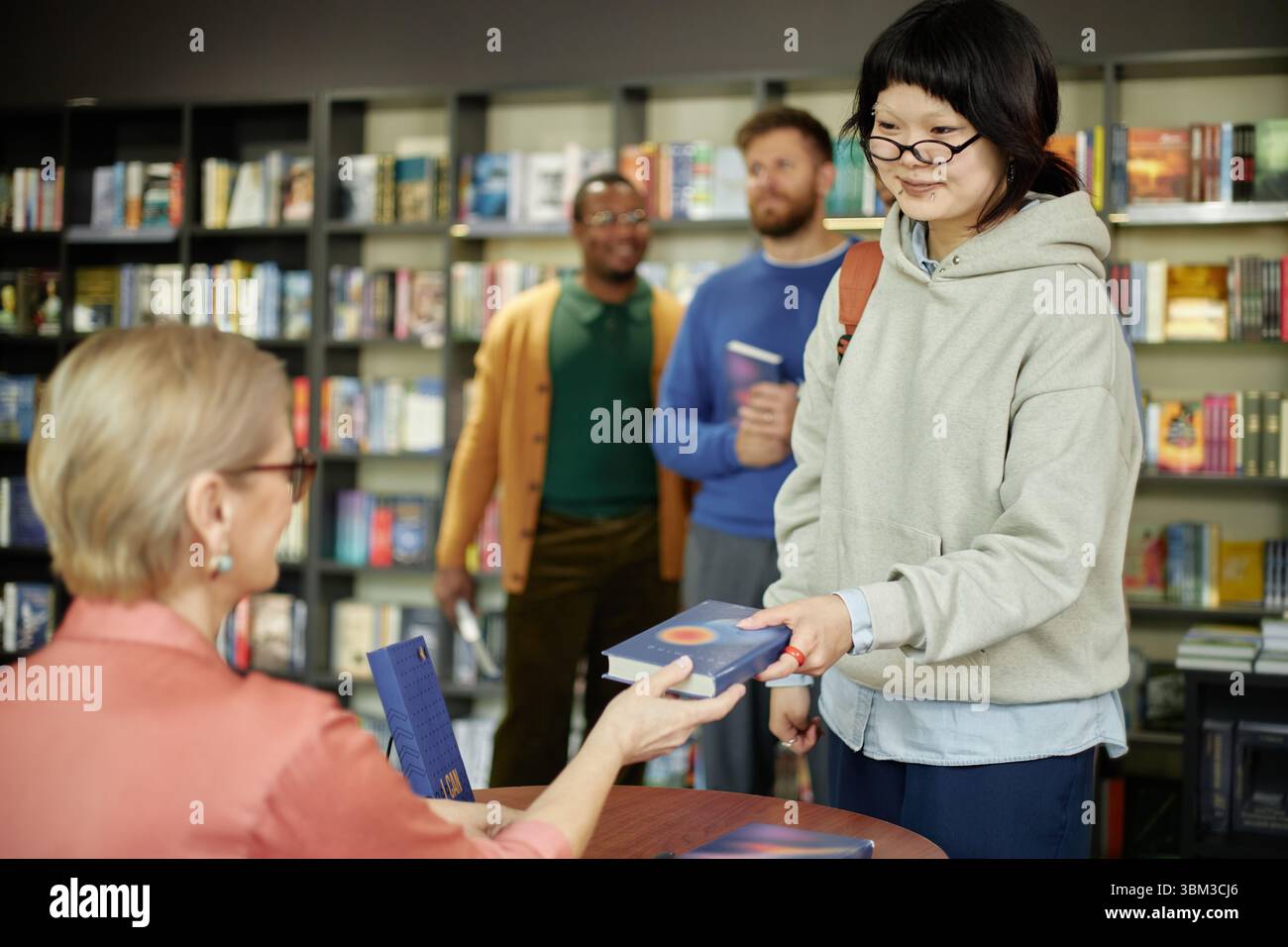 Jeune femme asiatique recevant livre avec autographe de l'auteur féminin Banque D'Images