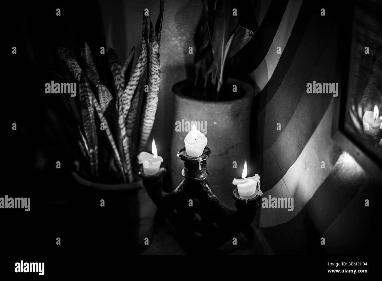 Des bougies allumées éclairent faiblement une plante un miroir et un drapeau aux nuances rouges à Essaouira Maroc Banque D'Images