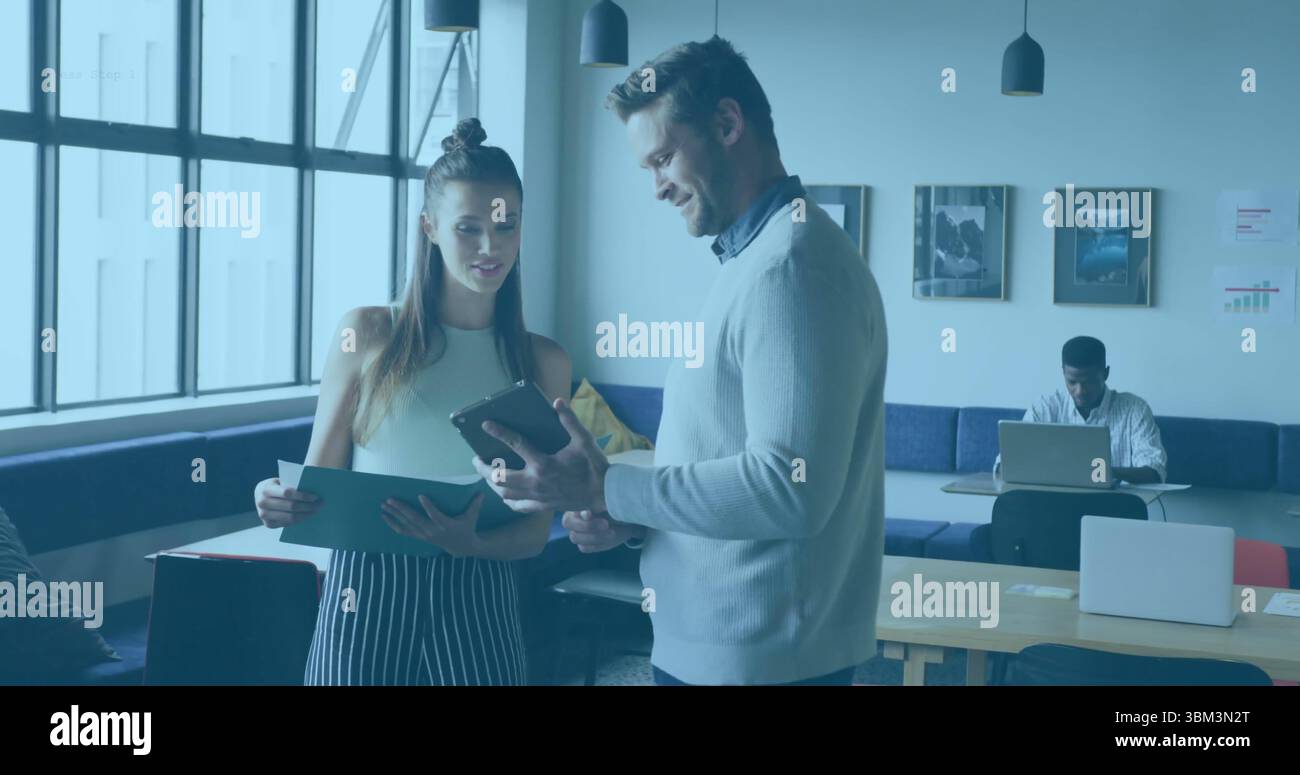 Deux collègues discutent des documents et tablette dans le salon de bureau, avec des tables en bois Banque D'Images