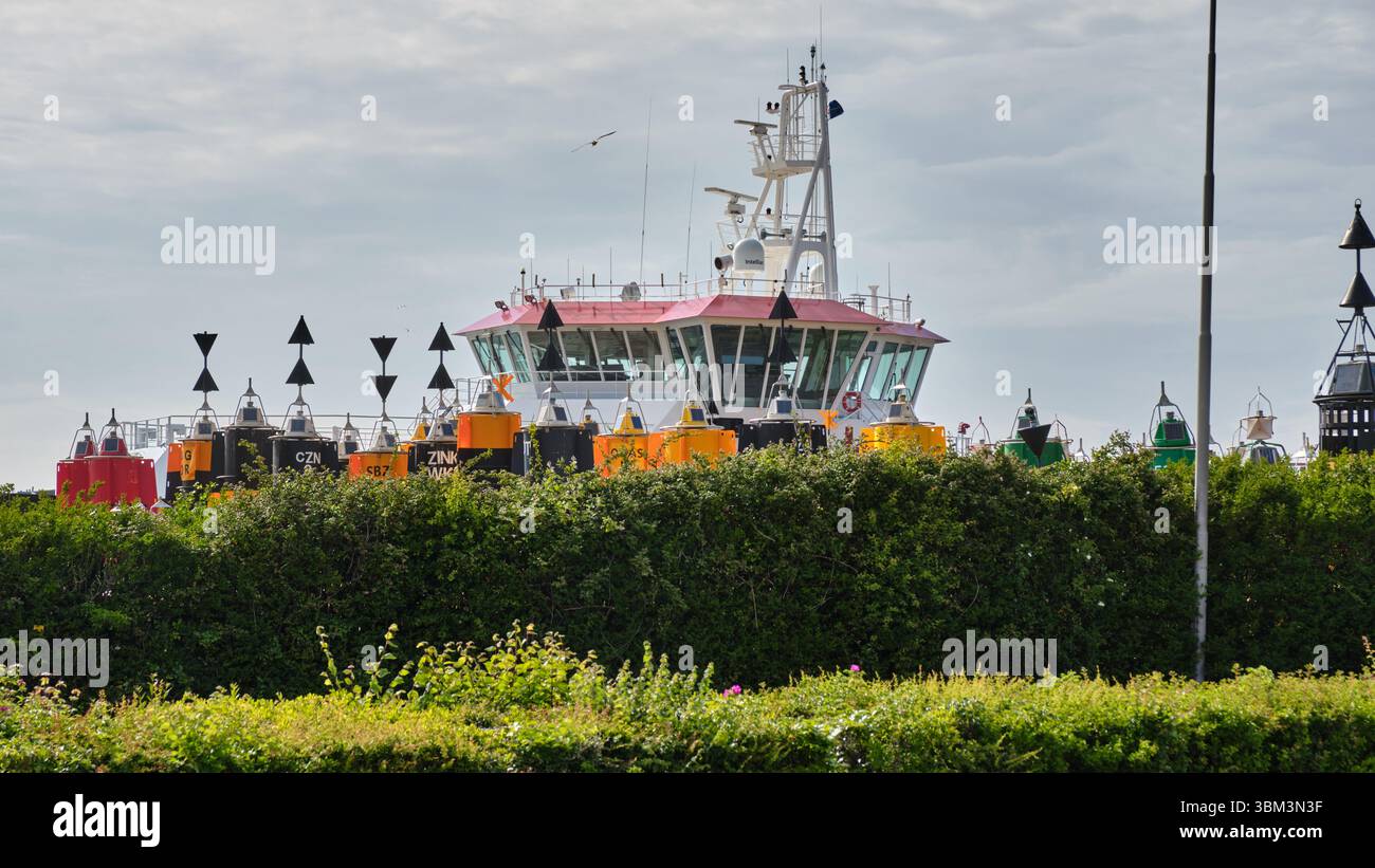 28 mai 2025 - Vlissingen-pays-Bas : navire des garde-côtes néerlandais amarré à un dépôt de bouées dans le port de Vlissingen avec des bouées de navigation colorées entreposées Banque D'Images