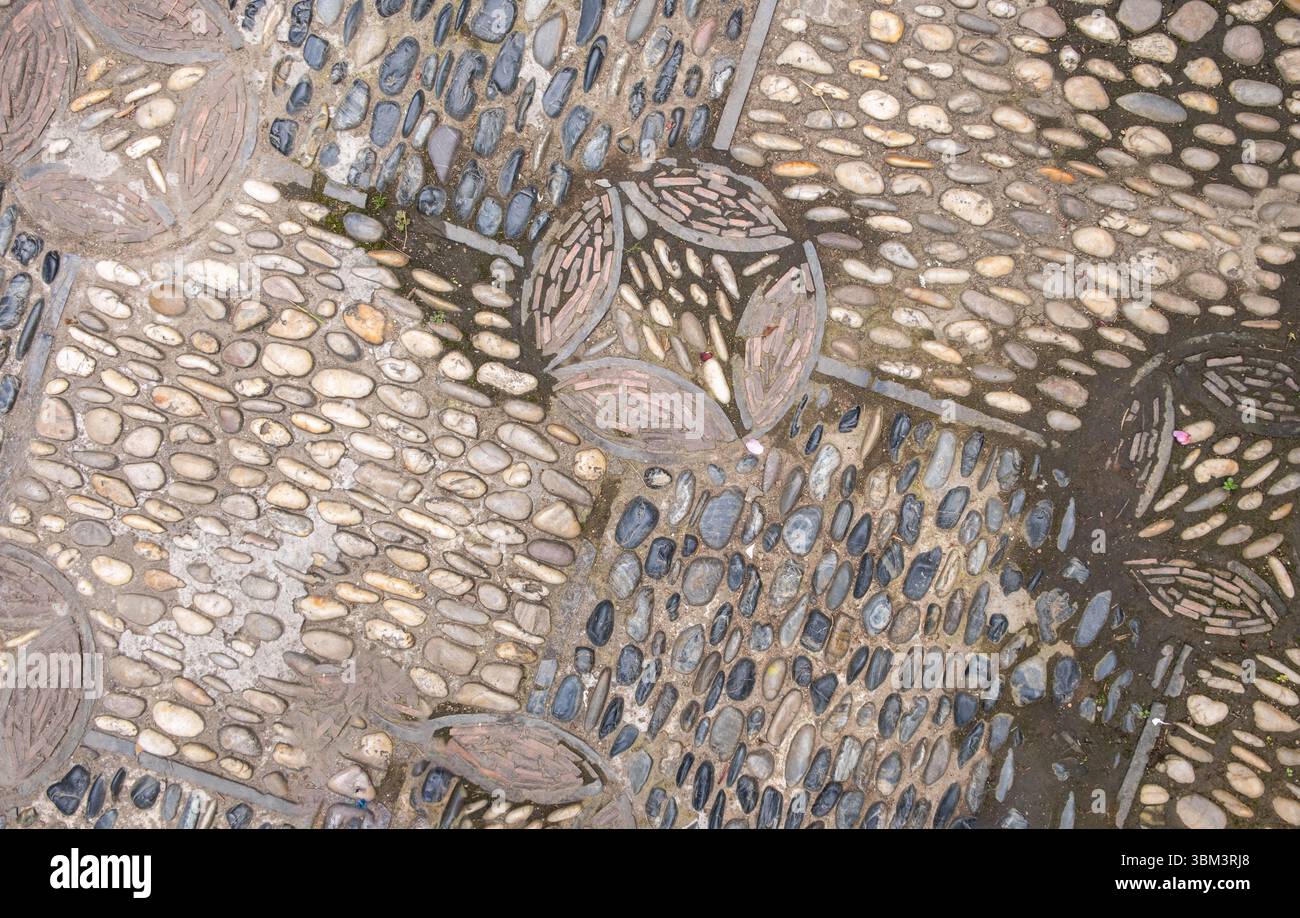 Fond de pavé traditionnel, pierres de rivière lisses disposées en motif. Ancien pavage de jardin chinois, texture vieillie Banque D'Images