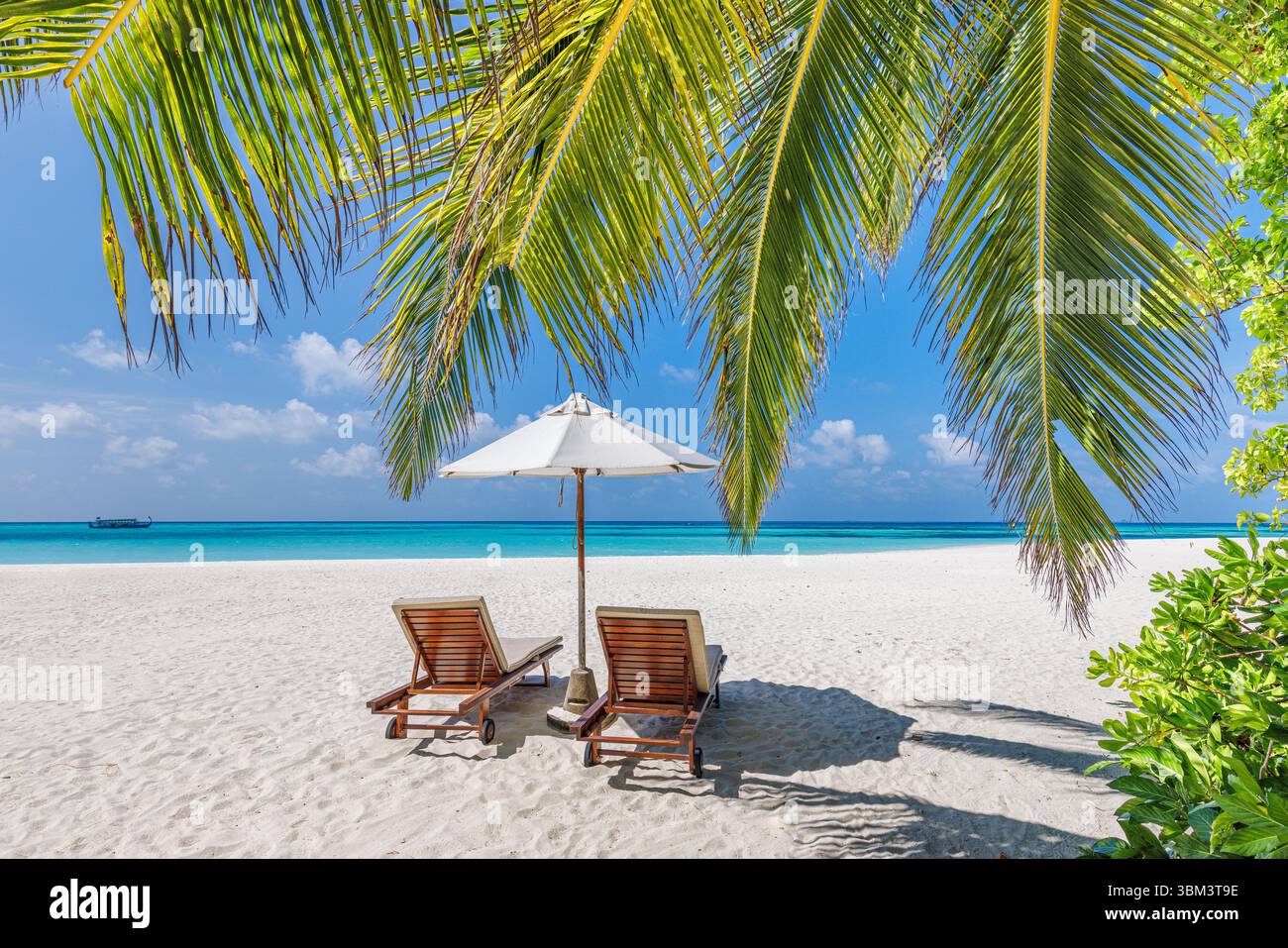 Belle plage romantique chaises de loisirs parasol sous le ciel ensoleillé, couple d'amour destination lune de miel paysage tropical pour des vacances reposantes Banque D'Images