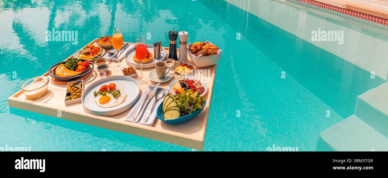 Matinée tropicale relaxante avec petit déjeuner flottant dans la piscine à débordement au complexe de luxe, fruits exotiques, œufs, jus servis moment de vacances pittoresque au bord de la piscine Banque D'Images