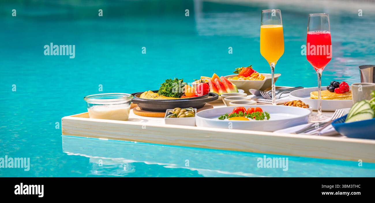 Matinée tropicale relaxante avec petit déjeuner flottant dans la piscine à débordement au complexe de luxe, fruits exotiques, œufs, jus servis moment de vacances pittoresque au bord de la piscine Banque D'Images