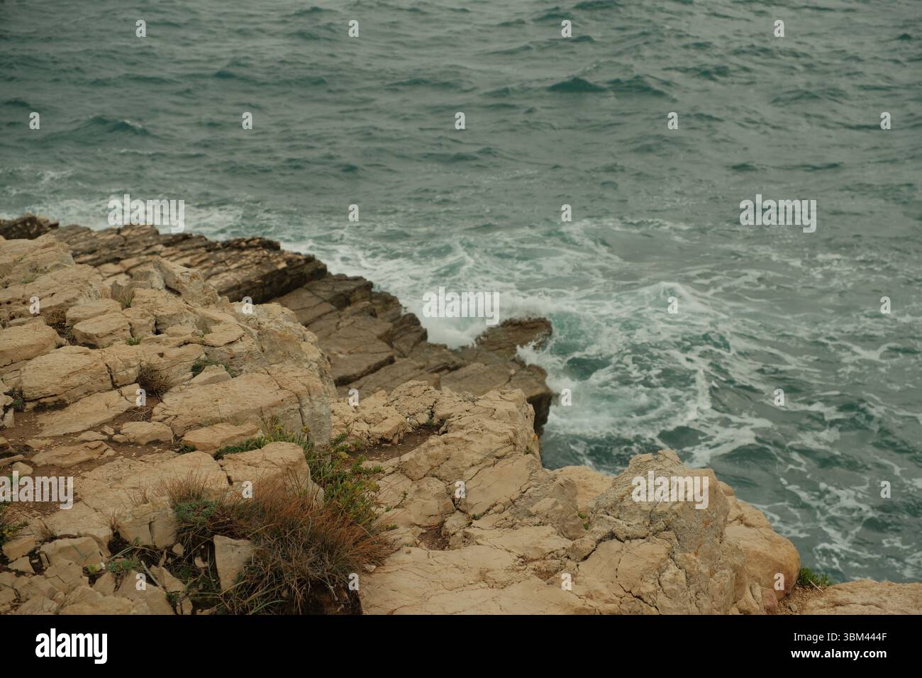 Des roches calcaires déchiquetées rencontrent la mer Adriatique lorsque les vagues s'écrasent sur le littoral accidenté. Le contraste dynamique de la pierre texturée. Banque D'Images