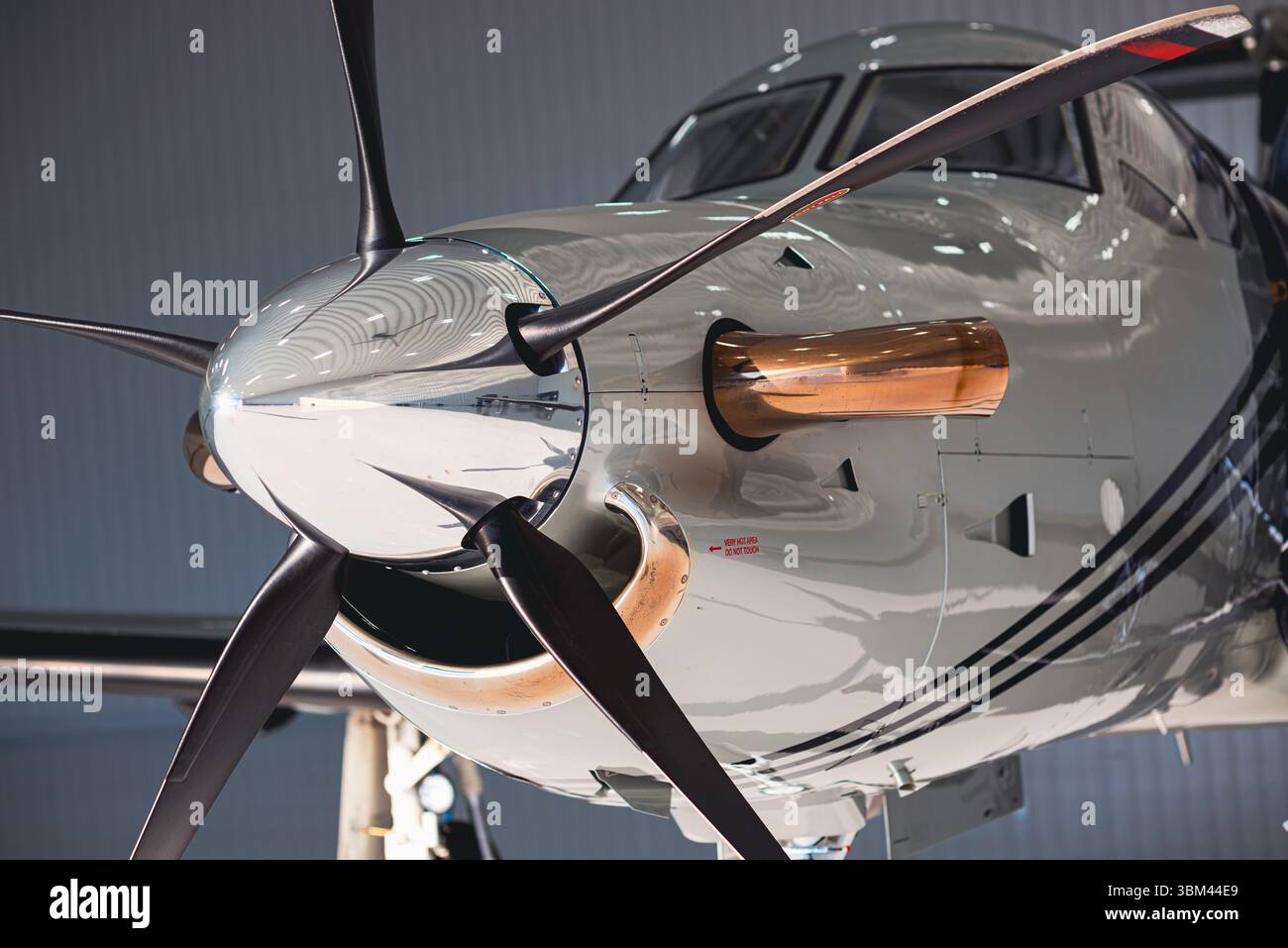 Vue latérale détaillée du nez et de l'hélice d'un avion à turbopropulseur, montrant la turbine, l'échappement et les capots polis dans la lumière du hangar. Banque D'Images