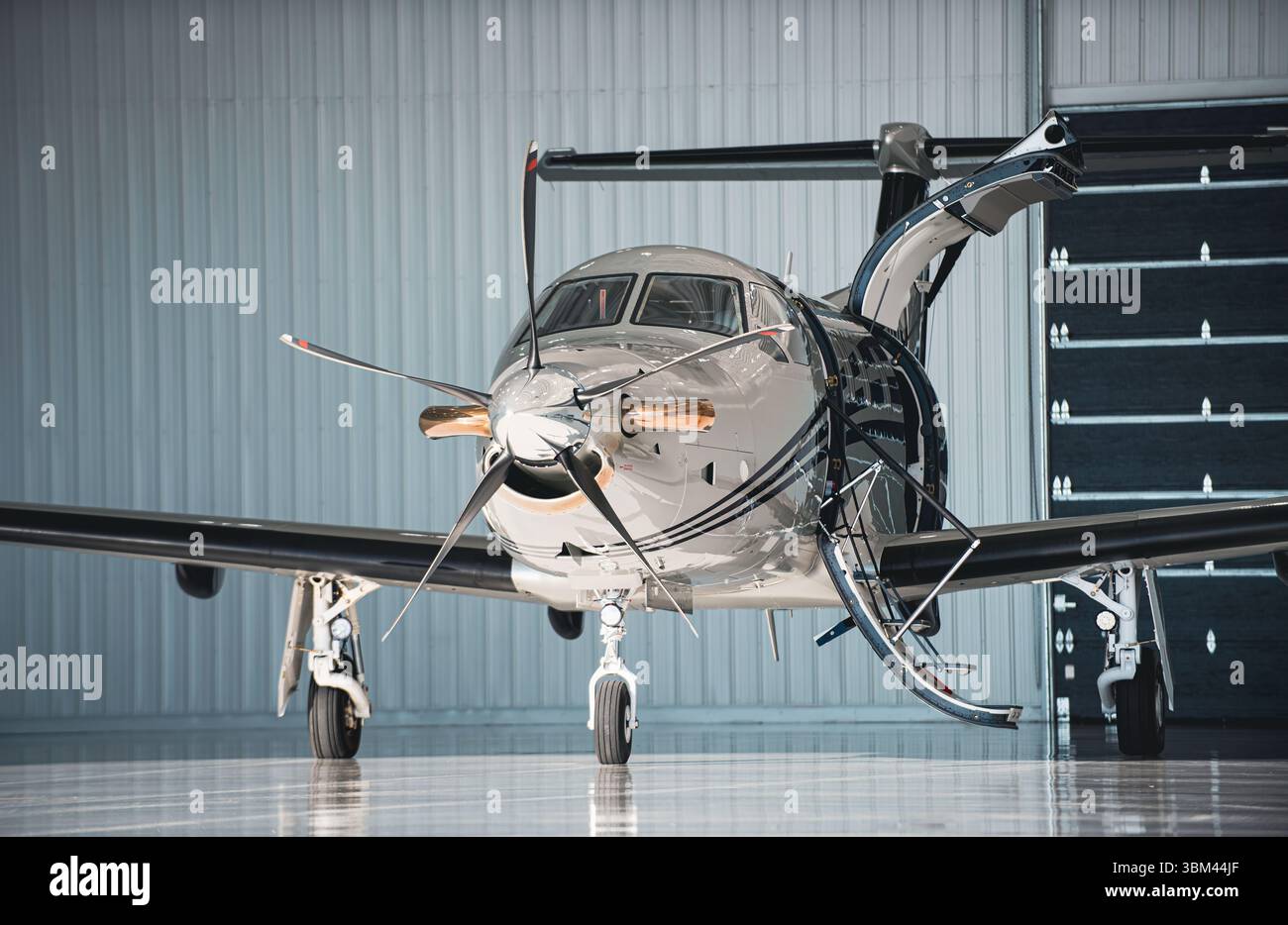 Vue de face d'un avion monomoteur à turbopropulseur stationné à l'intérieur d'un hangar avec la porte cargo arrière et les escaliers d'embarquement ouverts et le train avant visible. Banque D'Images