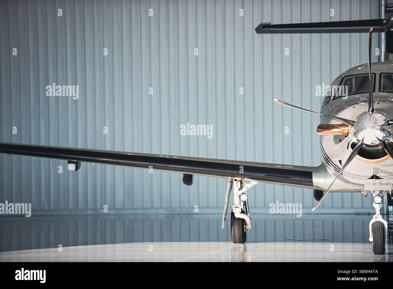 Vue partielle de face d'un avion à turbopropulseur stationnaire dans un hangar, encadré excentré avec train d'atterrissage et hélice visibles sous Li directionnel mou Banque D'Images