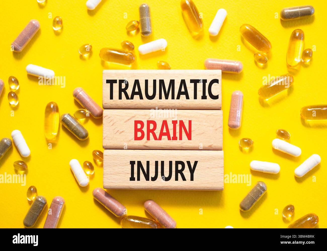 Symbole de lésion cérébrale traumatique. Mots conceptuels traumatisme crânien sur blocs de bois. Beau fond jaune avec des pilules. Soins de santé et traumatisme Banque D'Images