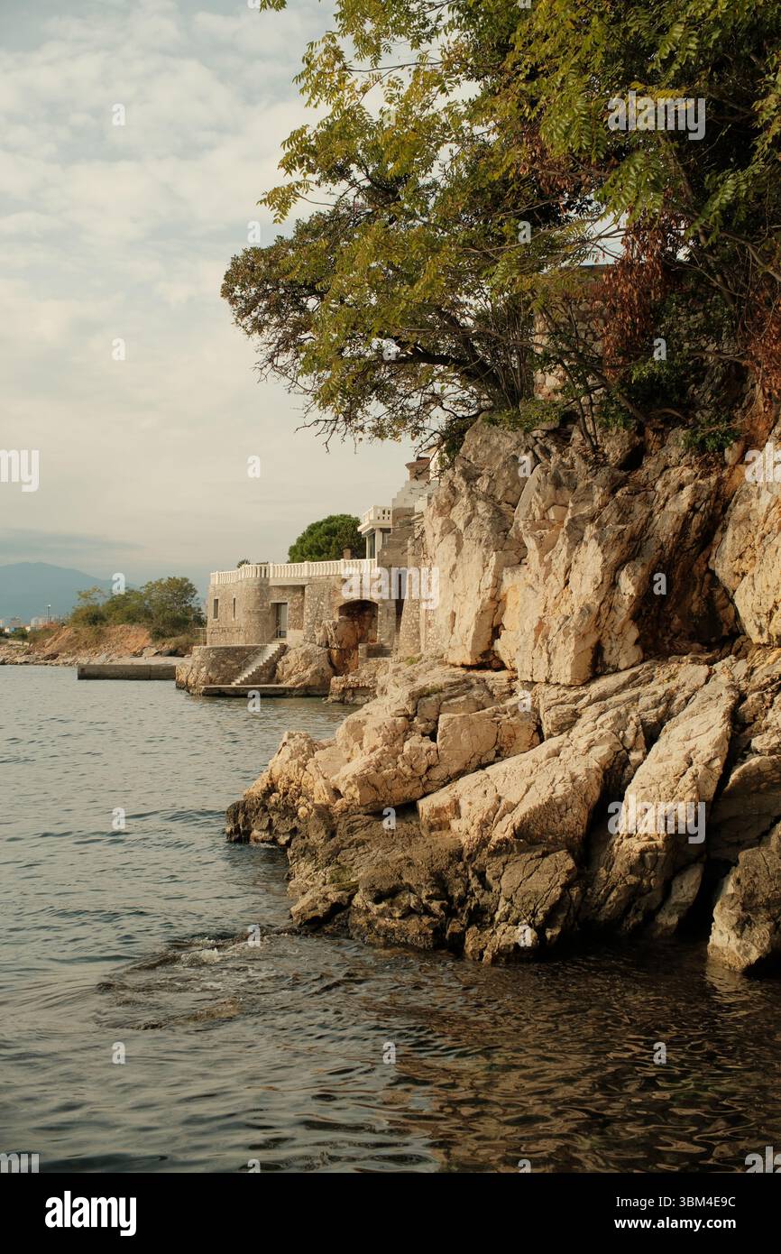 Les bâtiments en pierre se dressent de manière résiliente sur la côte croate accidentée, leurs façades altérées se mélangeant avec les roches calcaires naturelles dont ils émergent. Banque D'Images