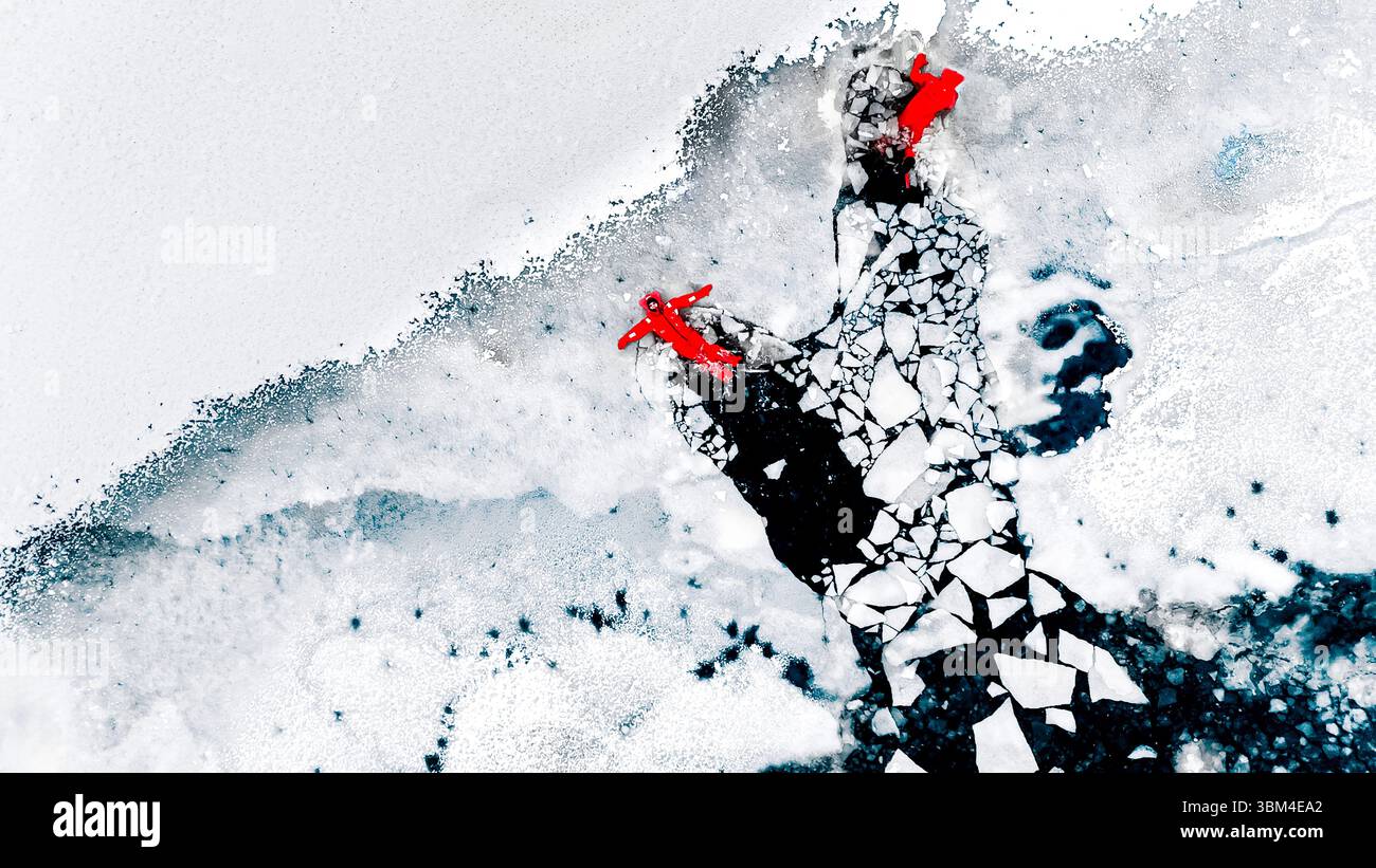 Vue aérienne de deux personnes de glace flottant sur l'eau glacée dans des combinaisons de survie rouge vif. Paysage glacé arctique. Aventure extrême, plongée sous glace, eau froide s Banque D'Images