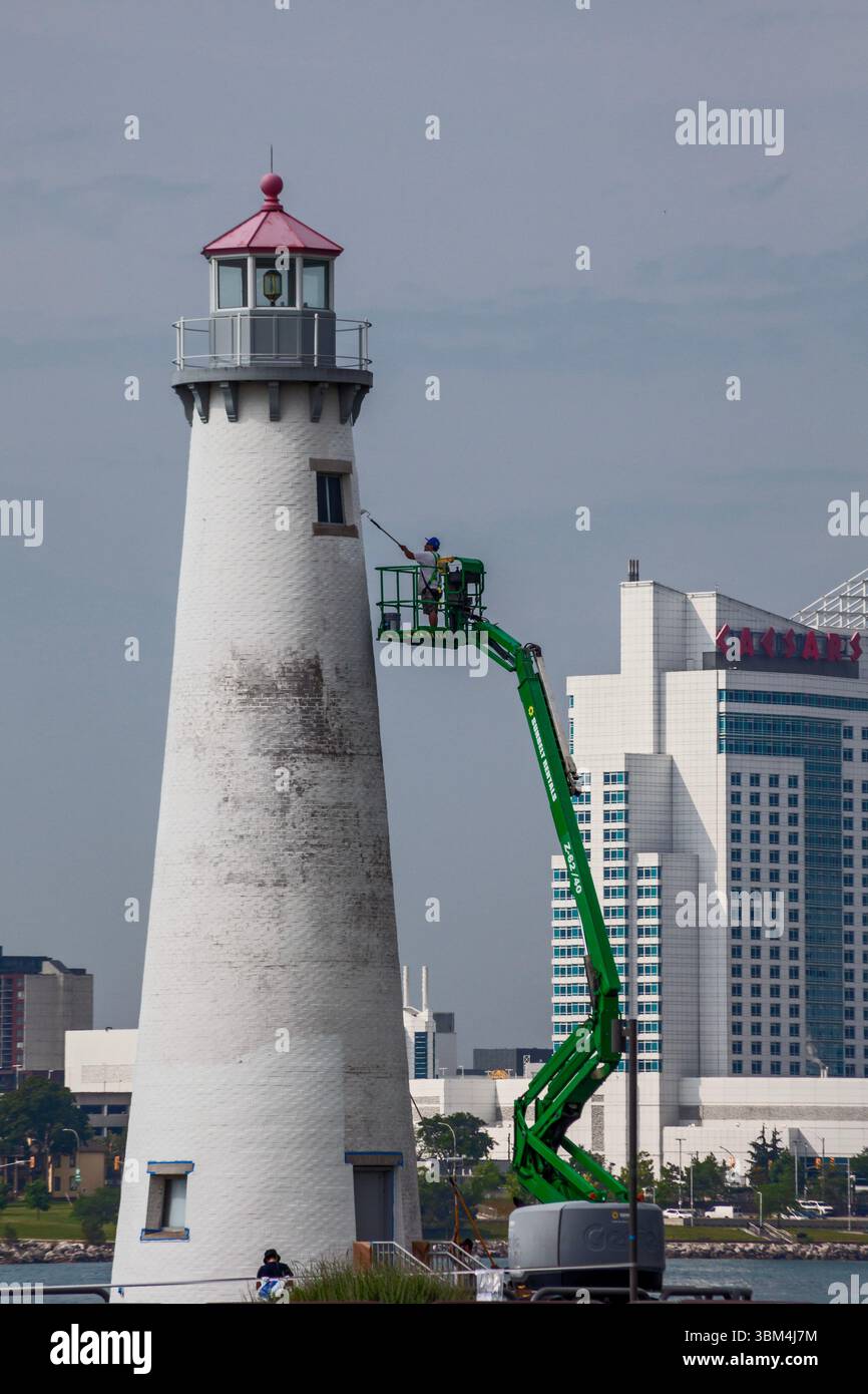 Detroit, Michigan - Un travailleur sur un ascenseur peint le phare du parc d'État de Milliken. Le phare est situé sur la rivière Détroit, près du centre-ville de Détroit. Caesa Banque D'Images
