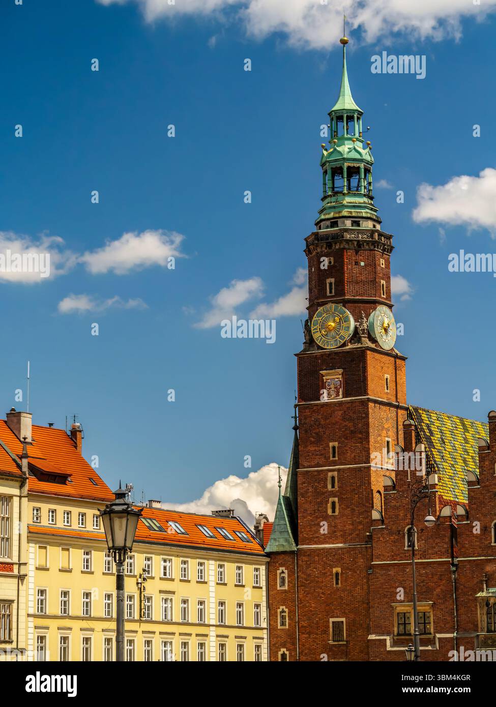Une scène vibrante avec une maison de ville historique avec tour de l'horloge entourée de charmants bâtiments colorés sous un ciel bleu ensoleillé et parsemé de nuages, Wrocla Banque D'Images