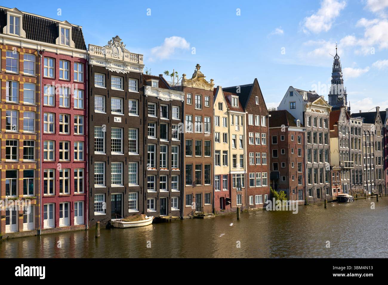 Maisons de danse Damrak à Sunshine Amsterdam pays-Bas. Les célèbres maisons de danse Damrak d'Amsterdam et les reflets du canal par une journée ensoleillée. Banque D'Images