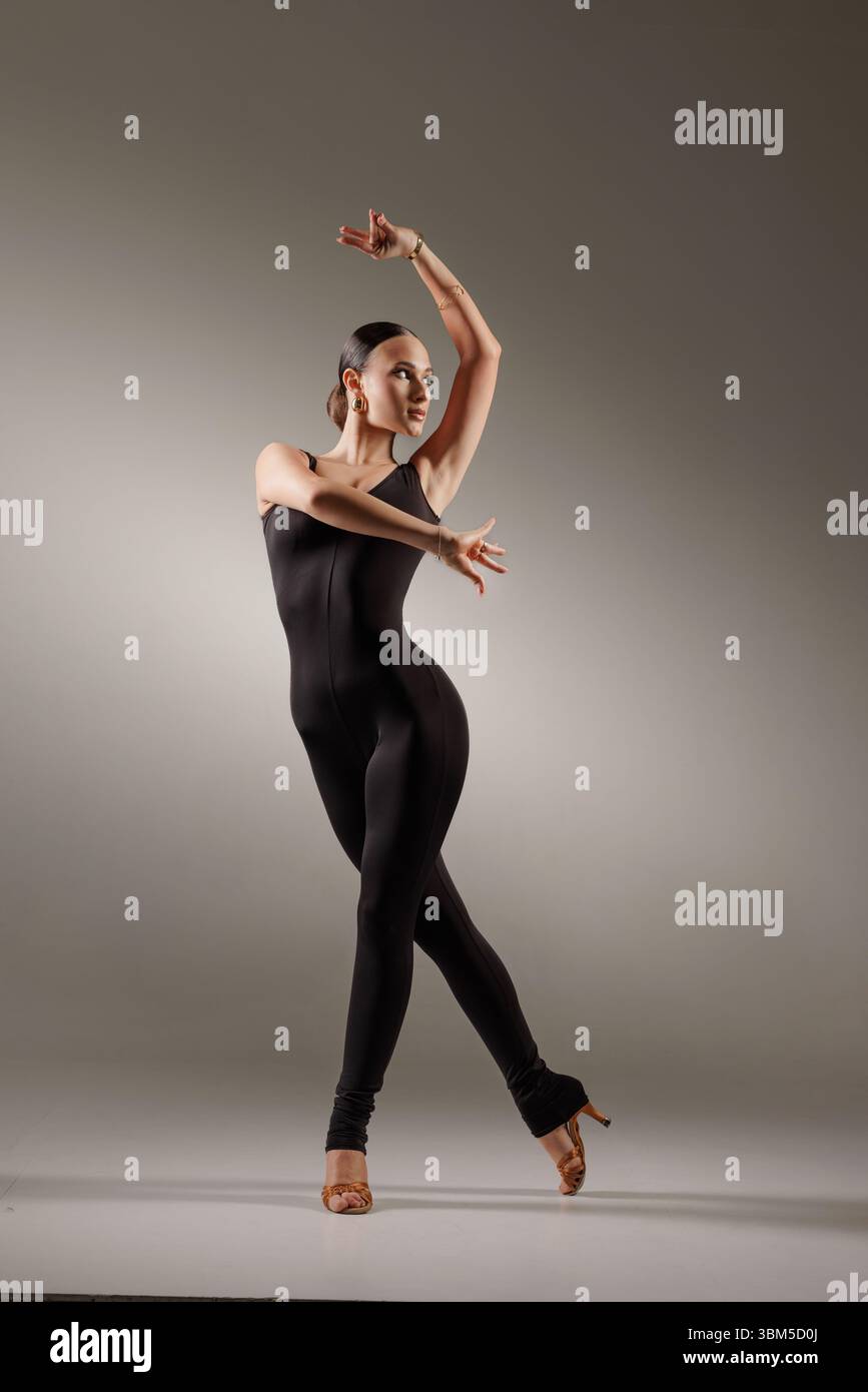 Danseuse féminine élégante en body noir frappe une pose de danse latine gracieuse dans un cadre de studio professionnel Banque D'Images