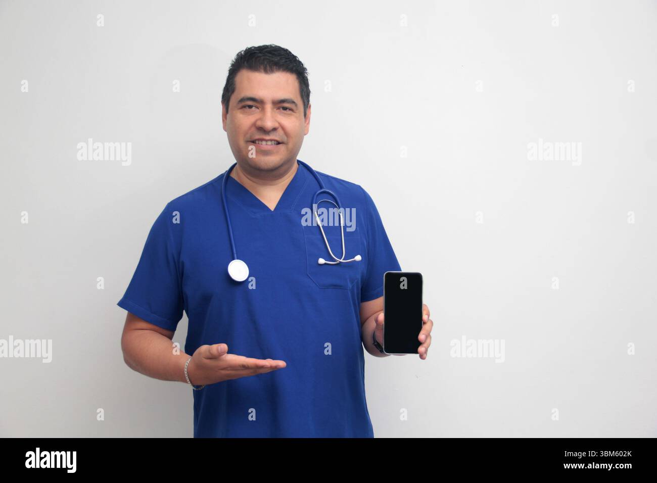 Un médecin latino-américain à la peau foncée avec un stéthoscope montre son téléphone portable pour avoir des consultations en ligne avec ses patients Banque D'Images Un médecin latino-américain à la peau foncée avec un stéthoscope montre son téléphone portable pour avoir des consultations en ligne avec ses patients Banque D'Images