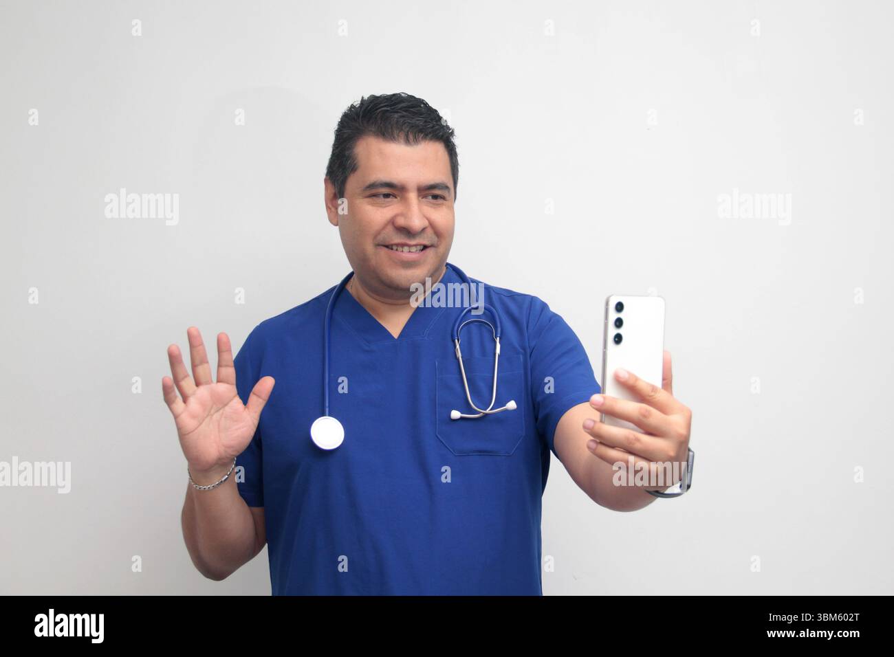 Un médecin latino-américain à la peau foncée avec un stéthoscope montre son téléphone portable pour avoir des consultations en ligne avec ses patients Banque D'Images Un médecin latino-américain à la peau foncée avec un stéthoscope montre son téléphone portable pour avoir des consultations en ligne avec ses patients Banque D'Images