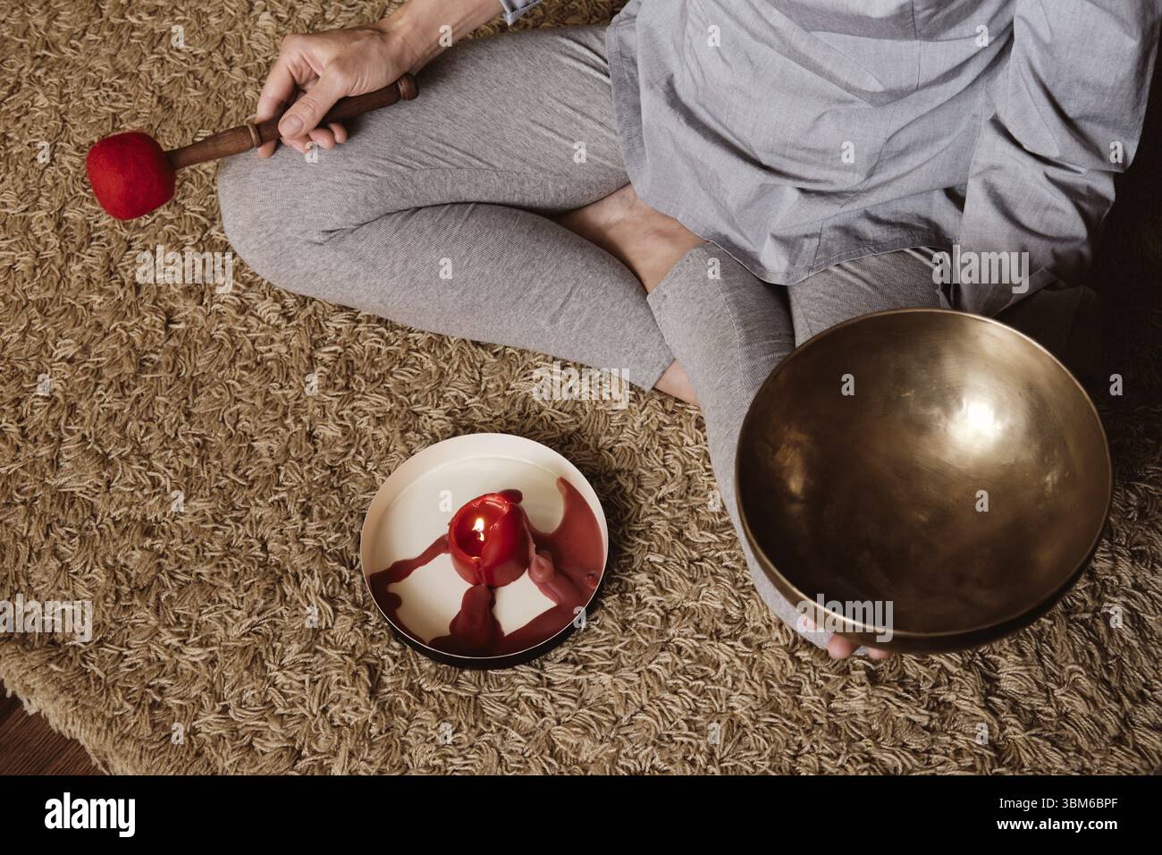 Une femme sans visage médite à la maison sur la moquette et joue sur le bol de chant en cuivre. Yoga et mode de vie sain Banque D'Images