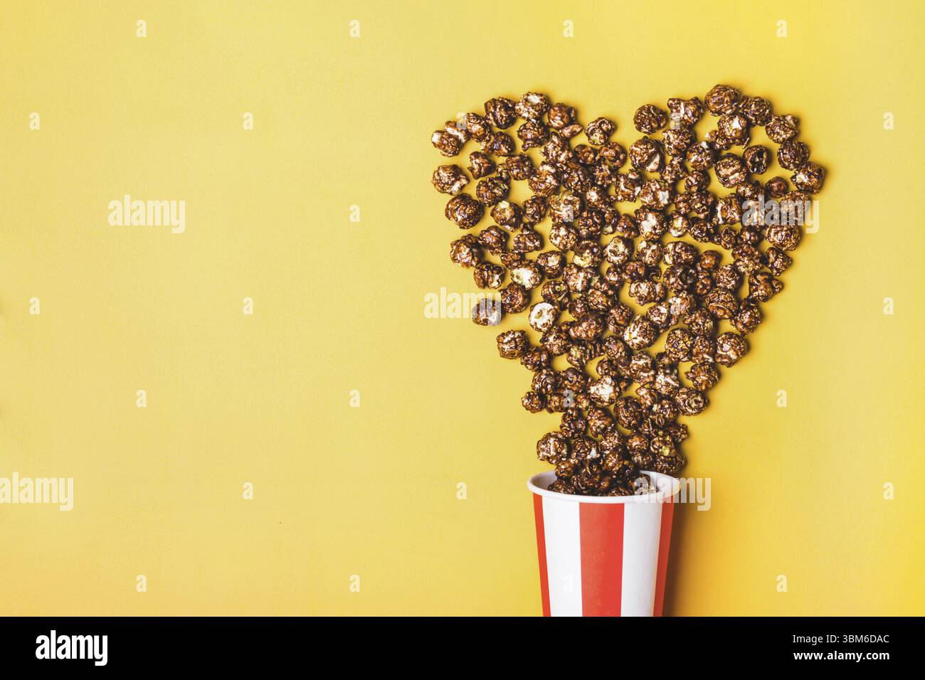 Pop-corn au chocolat doux dans une tasse rouge blanche rayée de papier Banque D'Images