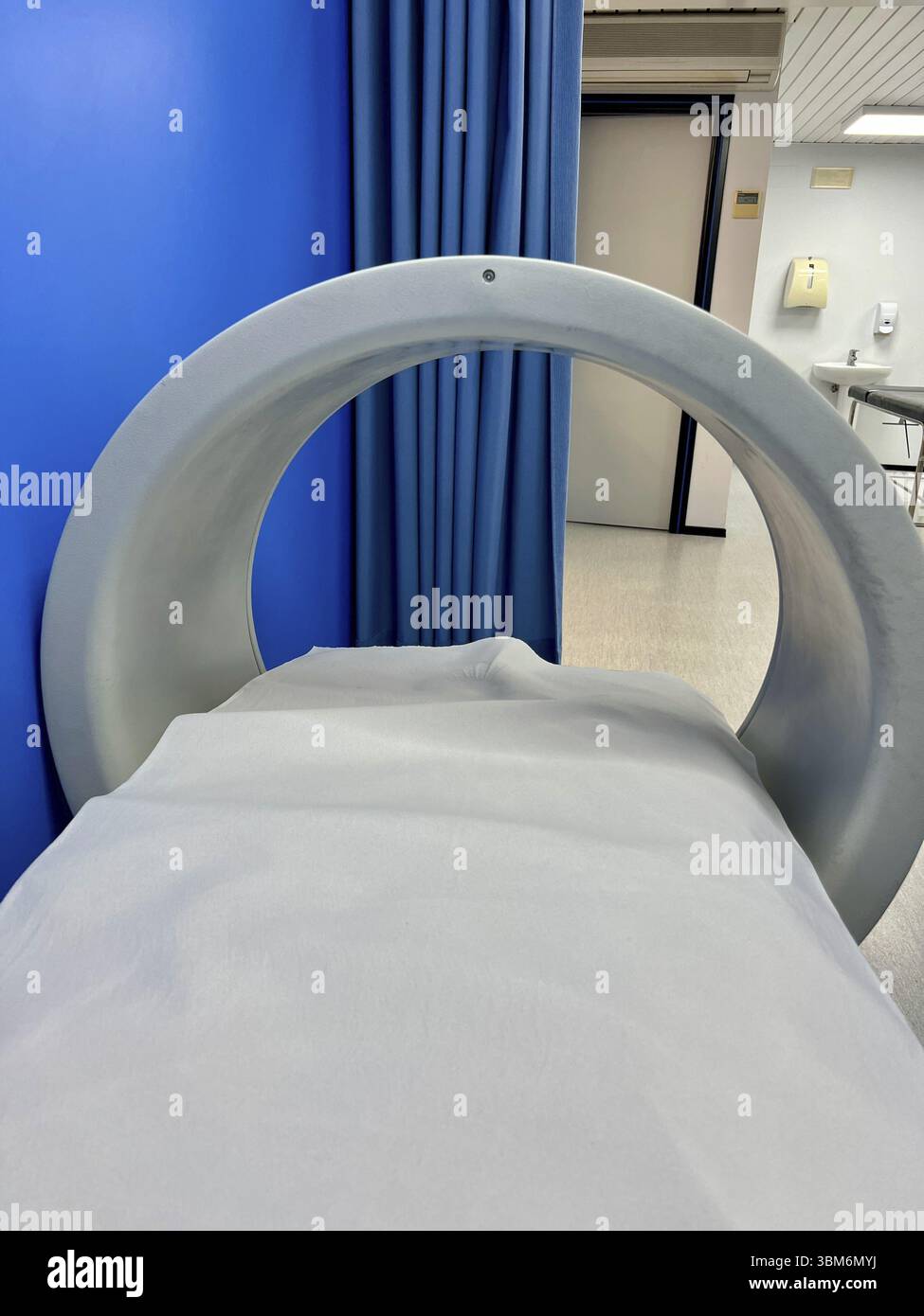 Un appareil IRM gris avec un rideau bleu derrière. Machine de magnétothérapie Banque D'Images
