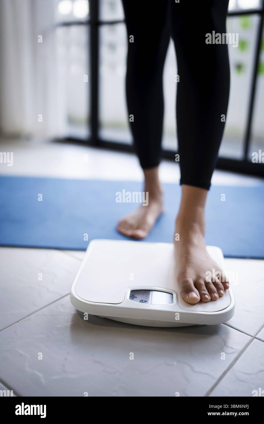 Perdez du poids. Régime gras et pieds de balance debout sur des balances électroniques pour le contrôle du poids. Instrument de mesure en kilogramme pour régime alimentaire Banque D'Images