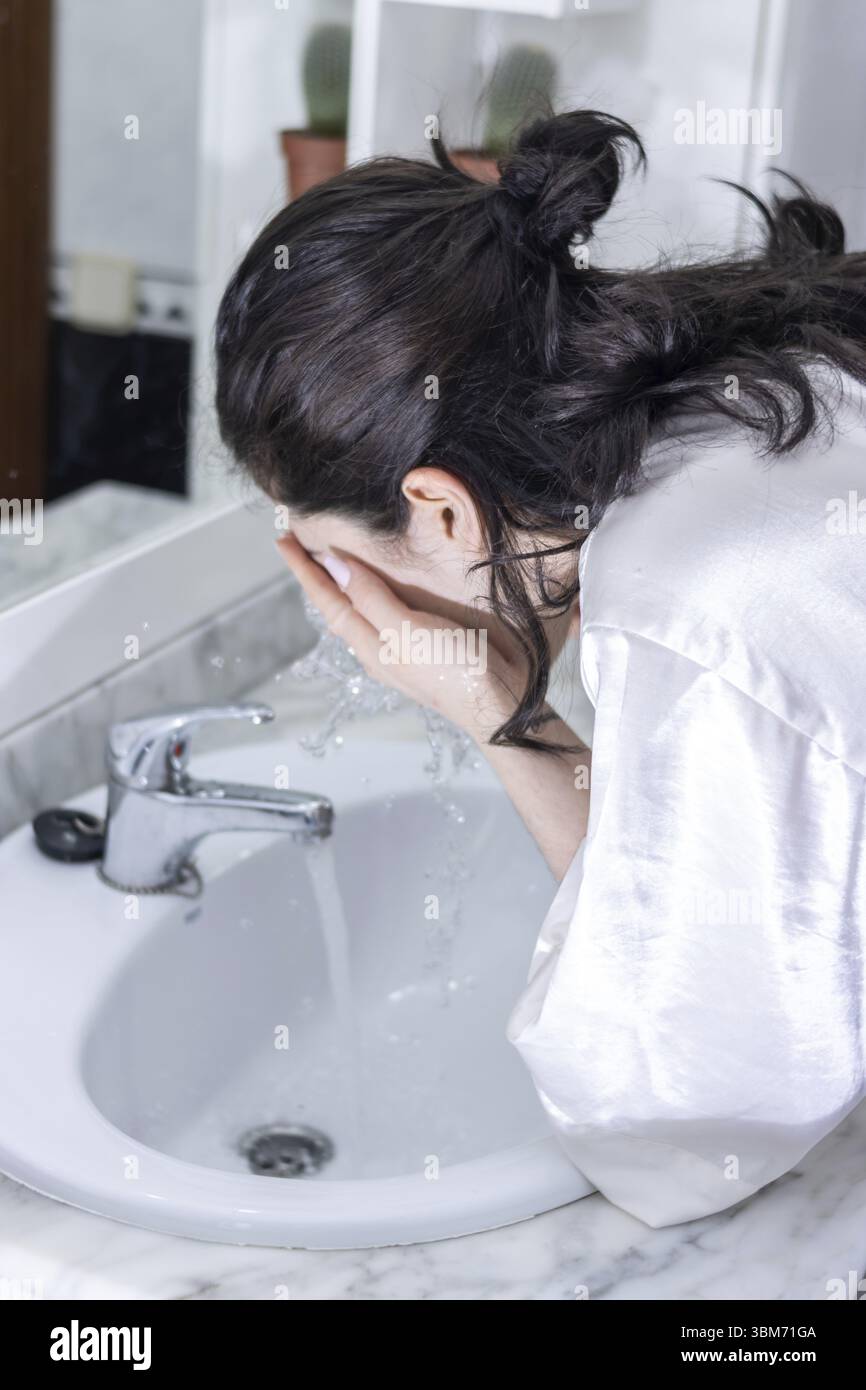 Femme se lavant le visage au lavabo de la salle de bain. Personne se lavant le visage le matin Banque D'Images