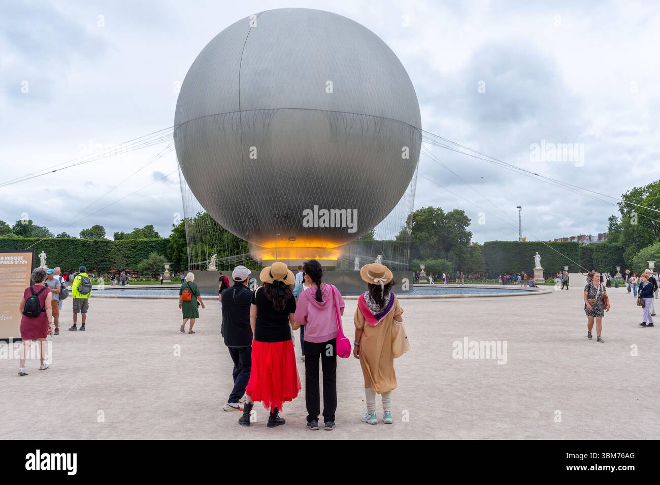 Touristes prenant des photos du Chaudron olympique dans le jardin des Tuileries à Paris. La flamme est faite d'un nuage de brouillard et de faisceaux de lumière Banque D'Images