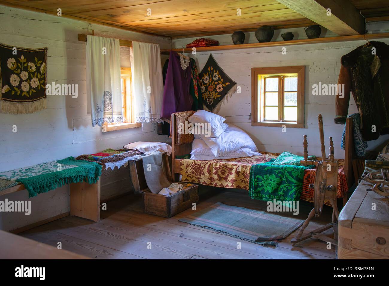 Une petite chambre avec un lit et quelques meubles. Le lit est recouvert d'une couverture colorée et d'oreillers Banque D'Images