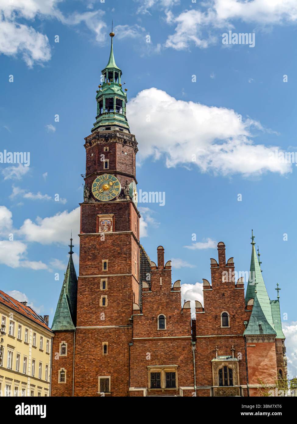 Une scène vibrante avec une maison de ville historique avec tour de l'horloge entourée de charmants bâtiments colorés sous un ciel bleu ensoleillé et parsemé de nuages, Wrocla Banque D'Images