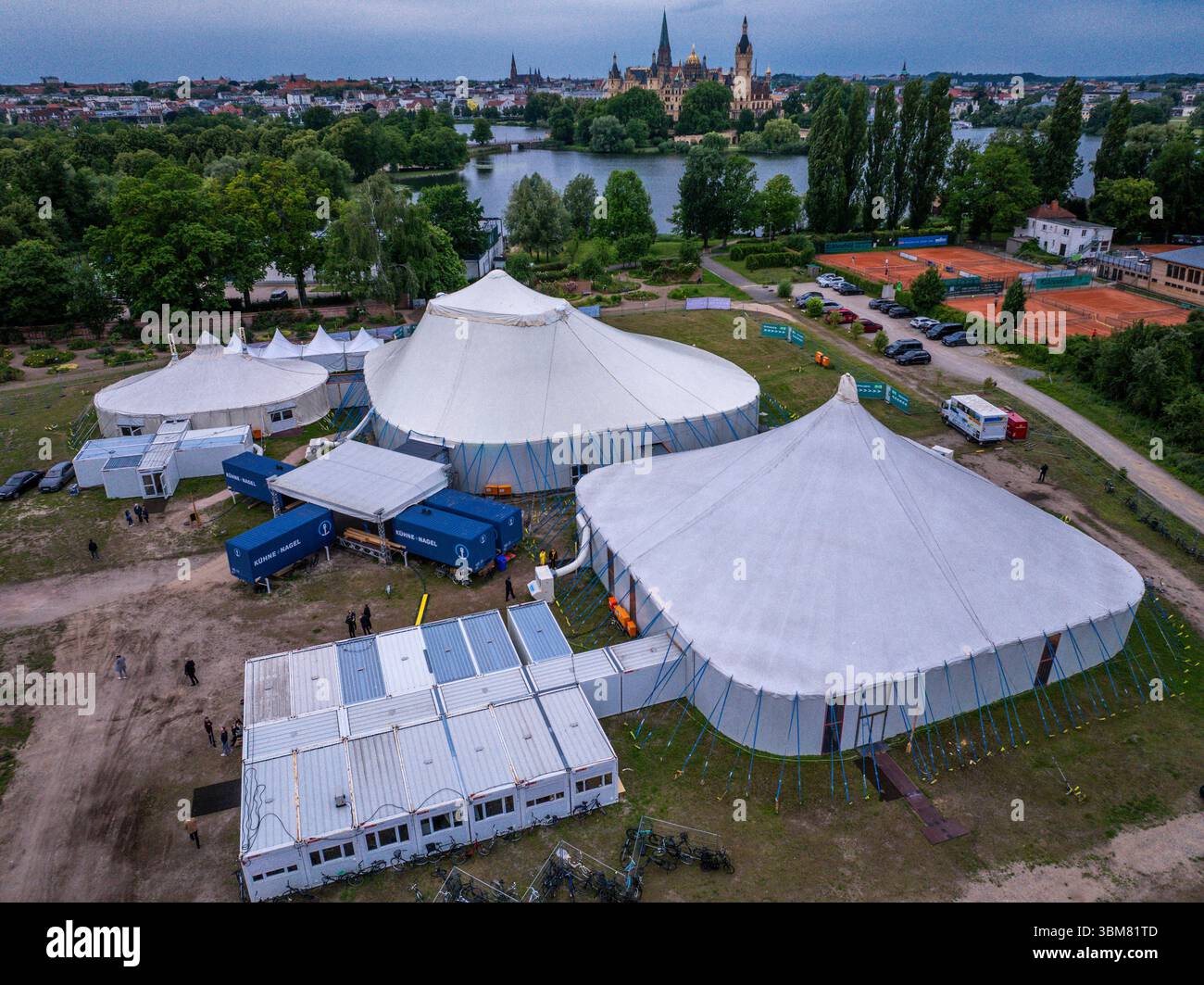 Schwerin, Allemagne. 24 juin 2025. Les acteurs, musiciens et techniciens du Théâtre d'État de Mecklembourg travaillent dans trois tentes et conteneurs spéciaux et répètent pour l'opérette 'la veuve joyeuse'. (Vue aérienne avec un drone). En raison de travaux de construction importants dans le bâtiment historique de la scène, six productions sont prévues pour la saison 2025/2026 dans la tente de théâtre sur le lac Schwerin. En plus des pièces de théâtre, ballets, opéras et opérettes, l'Orchestre d'État de Mecklembourg jouera également ses concerts dans la tente. Crédit : Jens Büttner/dpa/Alamy Live News Banque D'Images