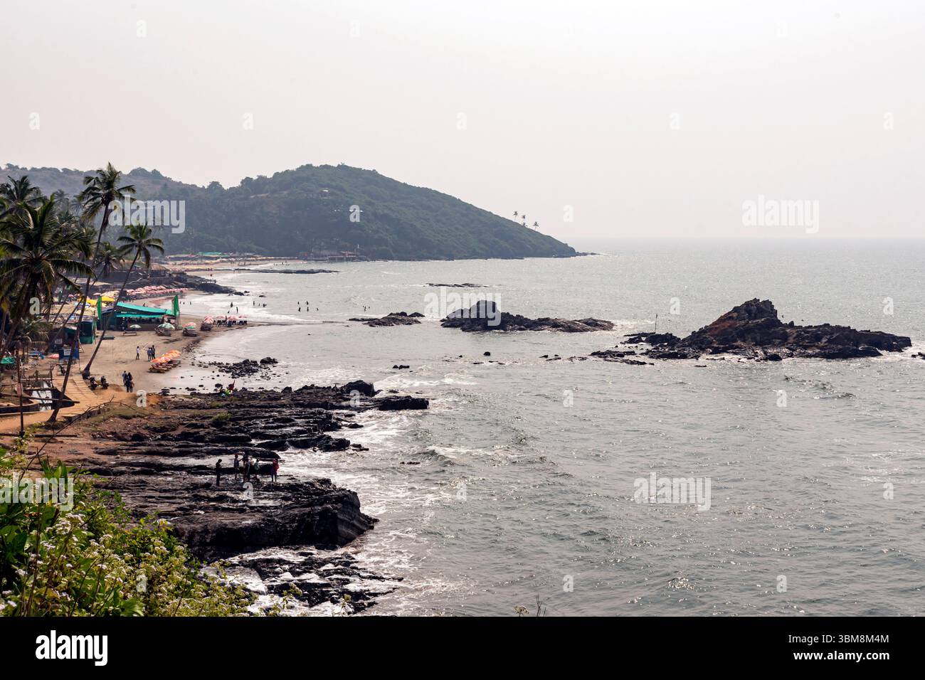 La lumière chaude du soleil illumine la paisible plage de Vagator à Goa, en Inde, où les gens se détendent, se promènent et explorent le littoral pittoresque. Banque D'Images