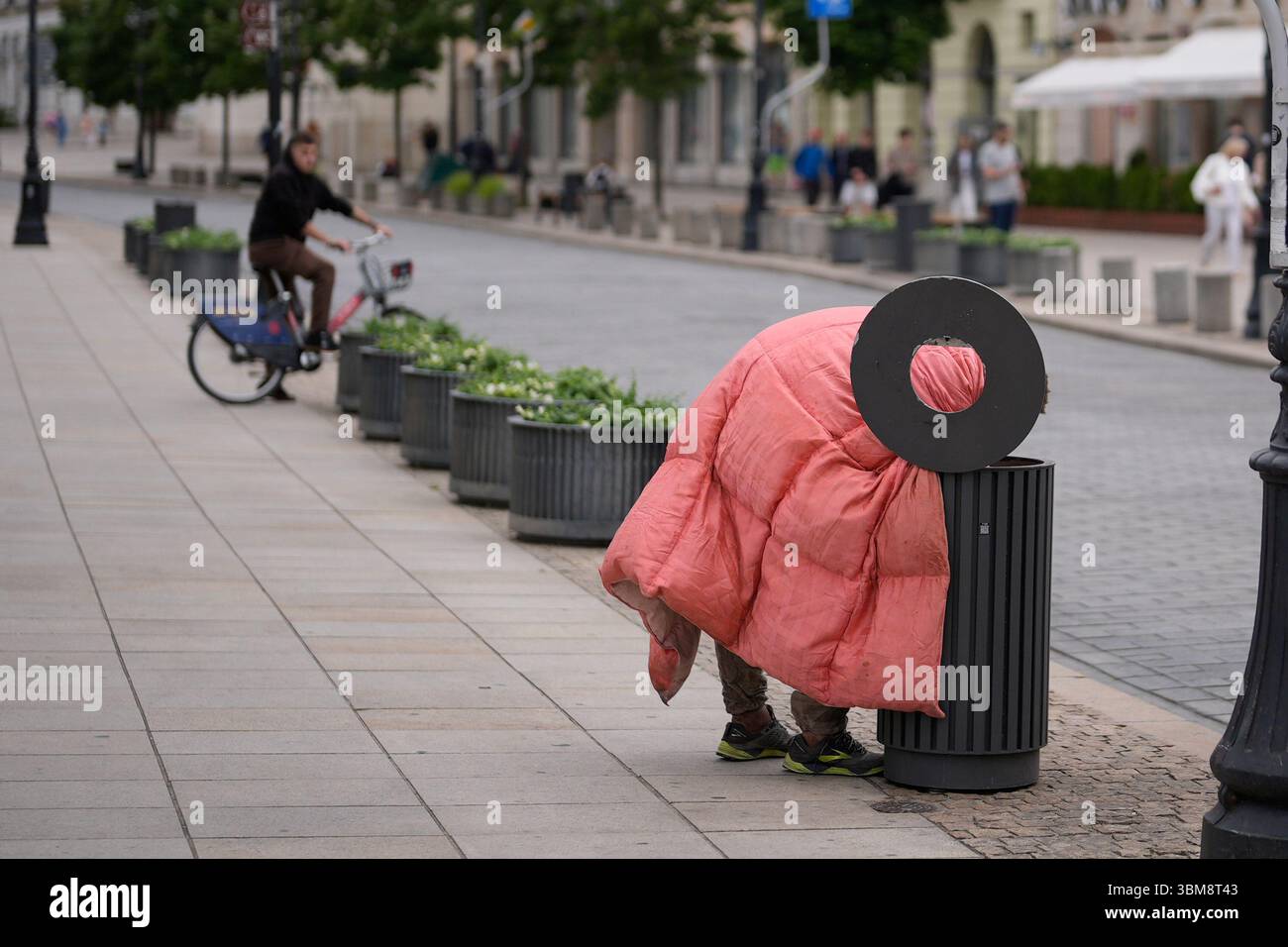 Varsovie, Pologne. 24 juin 2025. Un homme sans capuchon portant un sac de couchage regarde dans une poubelle à Varsovie, en Pologne, le 24 juin 2025. (Photo de Jaap Arriens/Sipa USA) crédit : Sipa USA/Alamy Live News Banque D'Images
