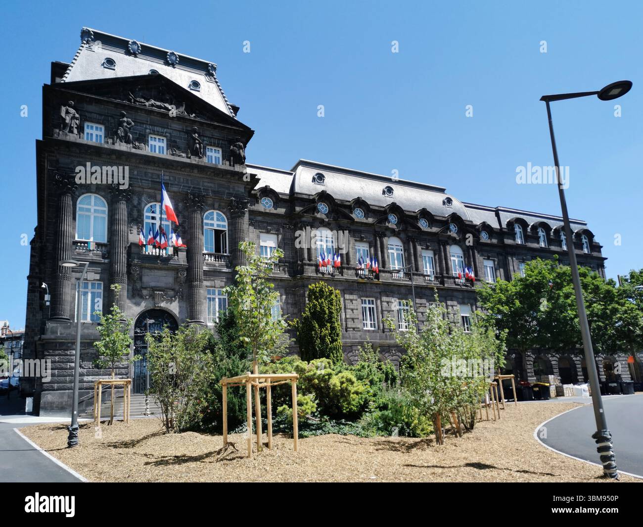 La préfecture de Clermont-Ferrand est ornée de drapeaux, entourée de verdure et éclairée par la lumière du soleil. Puy de Dôme, Auvergne , France Banque D'Images