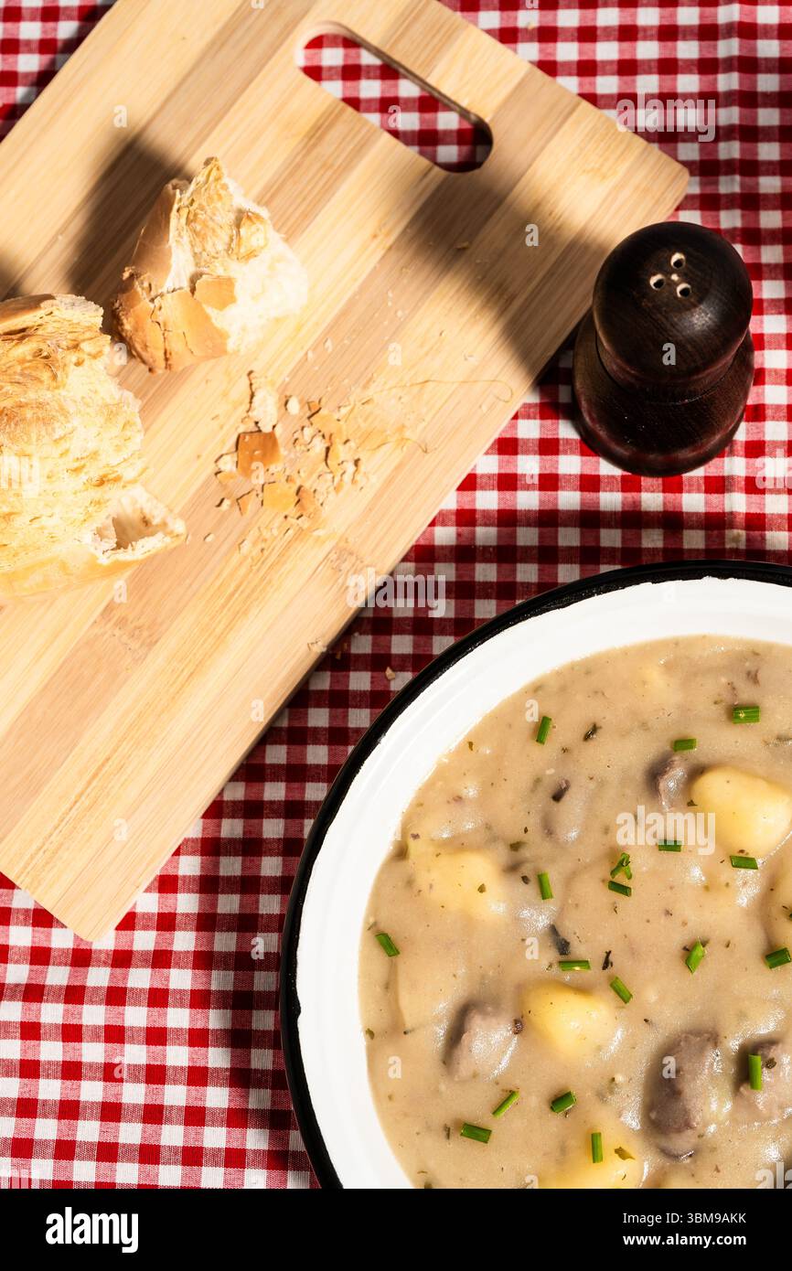 Soupe crémeuse de pommes de terre aux champignons et à la ciboulette servie sur une nappe à carreaux avec du pain Banque D'Images