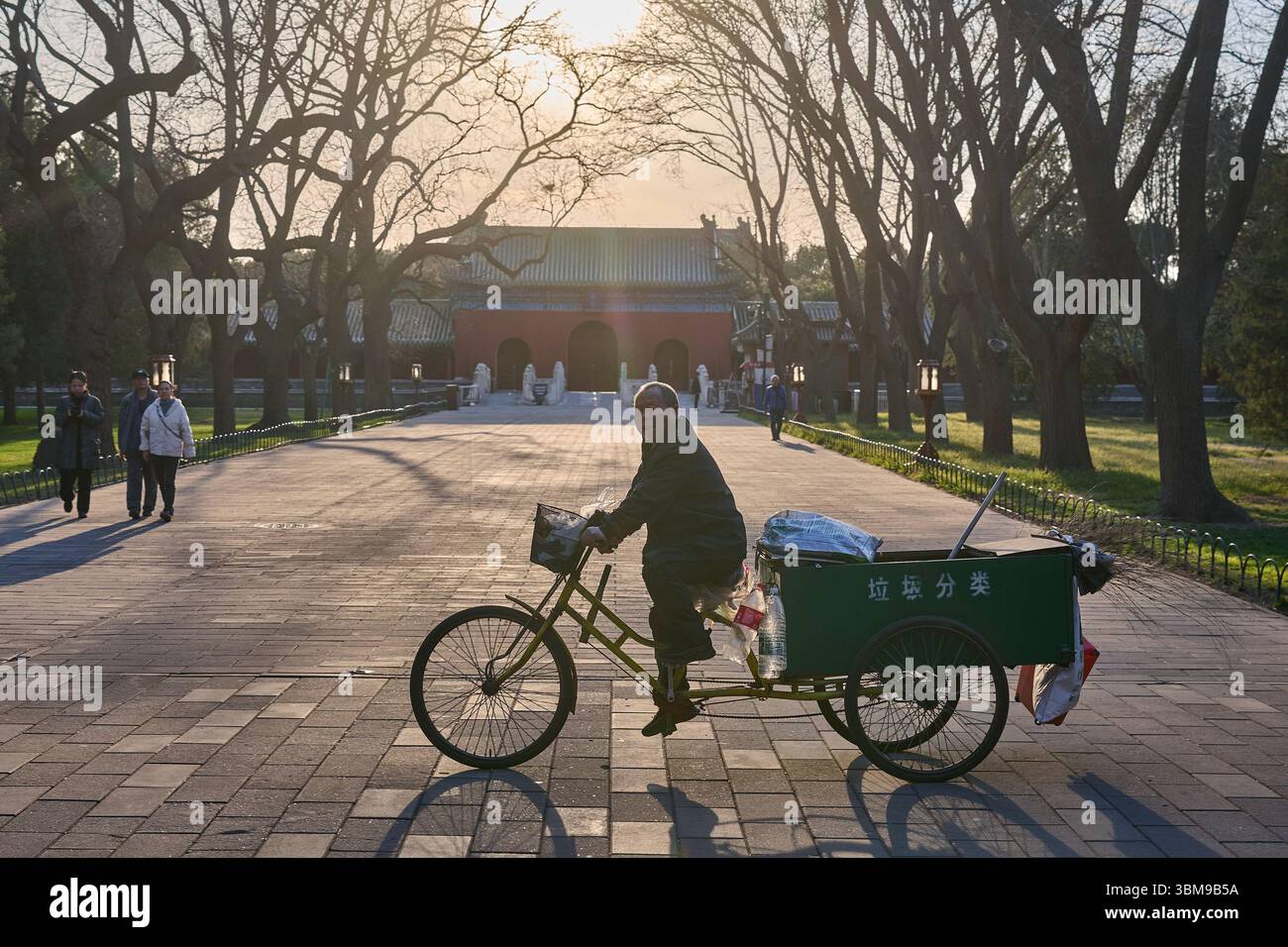 Travailleur de l'assainissement chevauchant un chariot tricycle au coucher du soleil dans un parc historique à Pékin Banque D'Images
