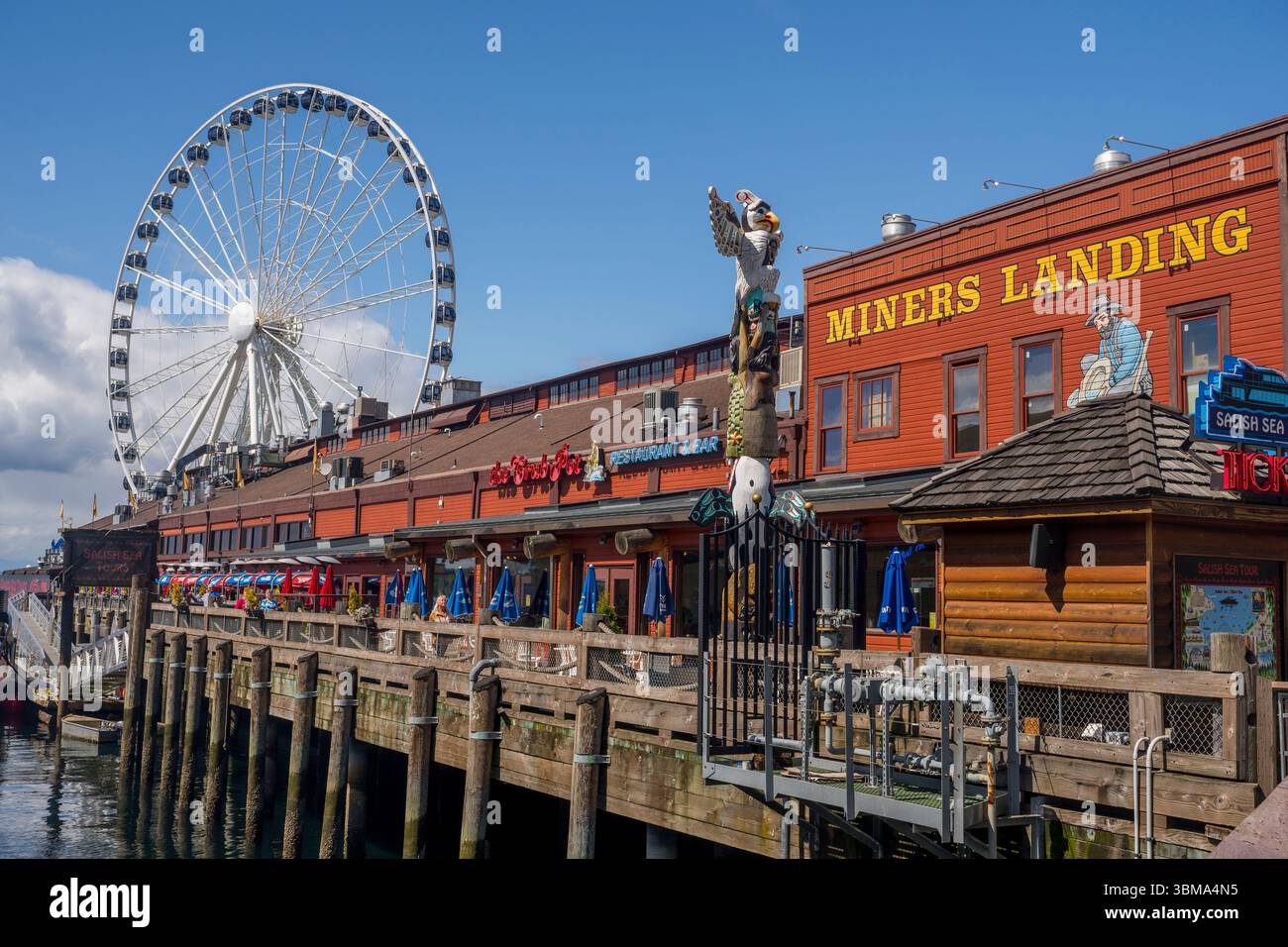 Vue du Miners Landing avec totem et grande roue sur le front de mer de Seattle, État de Washington, États-Unis. Banque D'Images