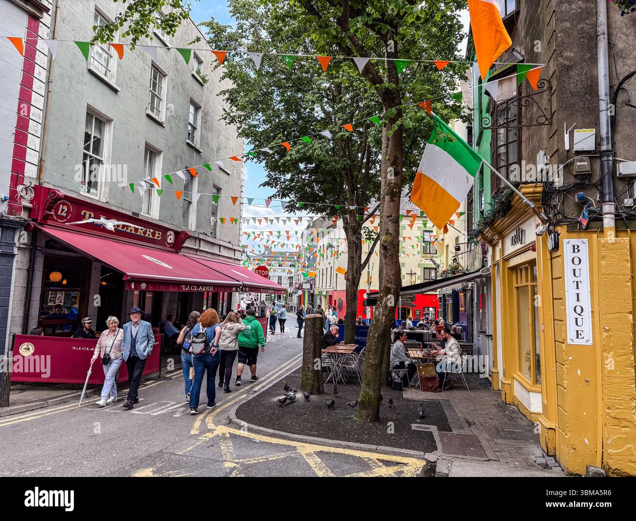 Shop Street. Rue piétonne animée à Galway, Irlande, avec des magasins, pubs, restaurants, touristes, et drapeaux irlandais. Banque D'Images