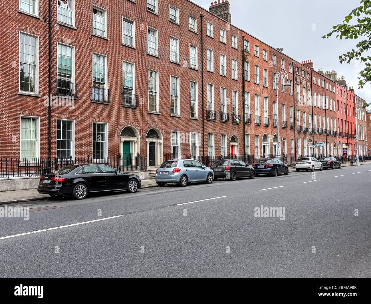 Voitures garées le long d'une rue devant des bâtiments historiques géorgiens à Dublin, Irlande. Banque D'Images