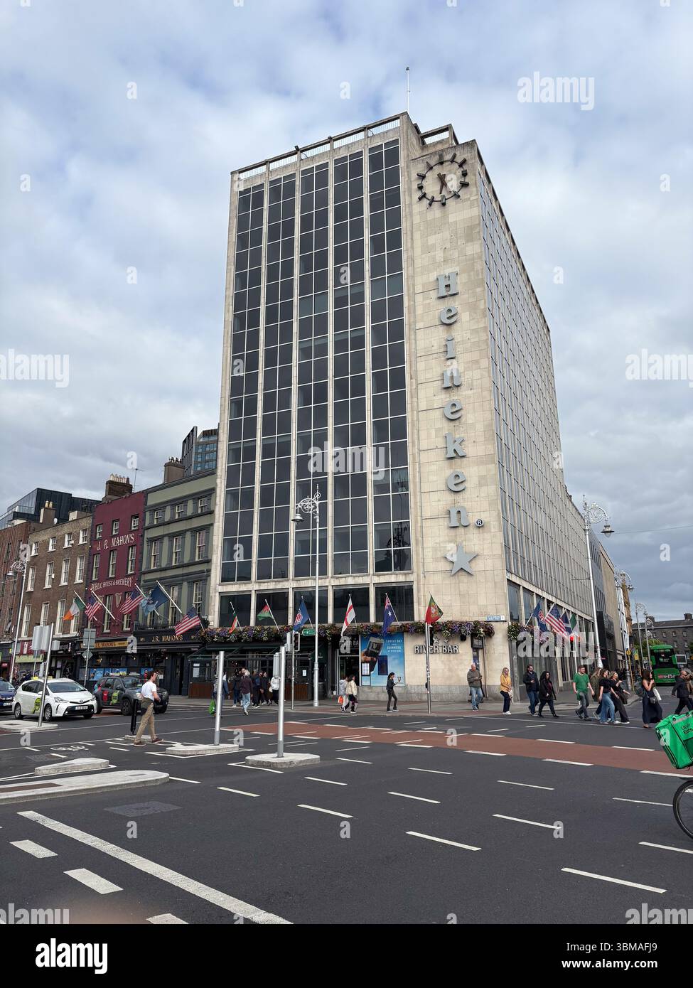 Bâtiment Heineken dans le centre-ville de Dublin. Immeuble de bureaux moderne avec horloge et drapeaux donnant sur la rue avec piétons. Banque D'Images