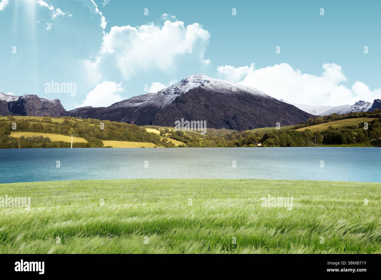 La conception plate montre une prairie verte qui coule dans un lac bleu avec une montagne enneigée et des nuages Banque D'Images