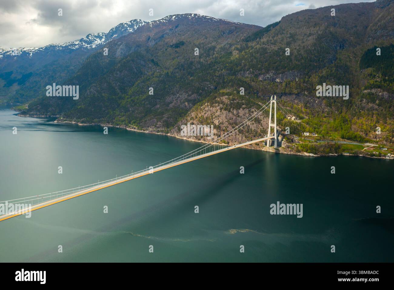 Hardanger Bridge enjambe gracieusement un vaste corps de fjord avec des montagnes imposantes formant une toile de fond spectaculaire. Pont suspendu moderne avec des tours proéminentes Banque D'Images
