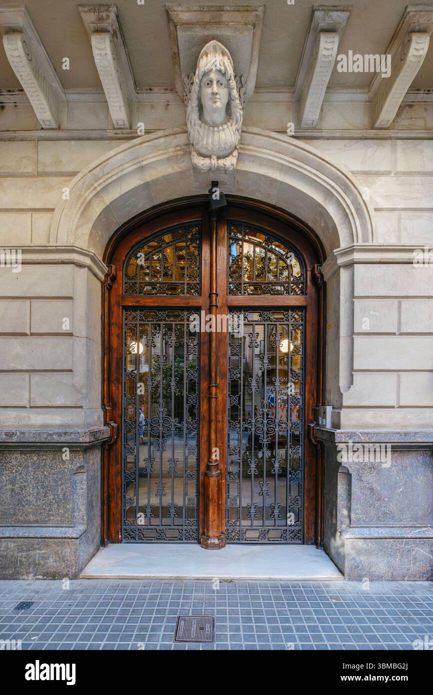 Porte d'entrée en bois ornée d'Un bâtiment classique de Barcelone, avec des détails architecturaux. Design espagnol historique, façade urbaine, Elemen décoratif Banque D'Images