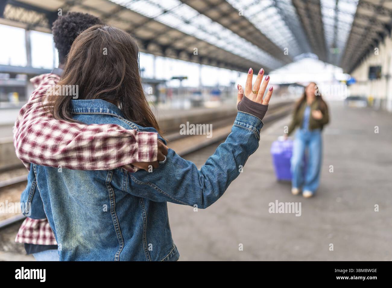 Couple saluant leur ami à la gare, partageant un moment sincère rempli de câlins et de sourires avant le début du voyage Banque D'Images