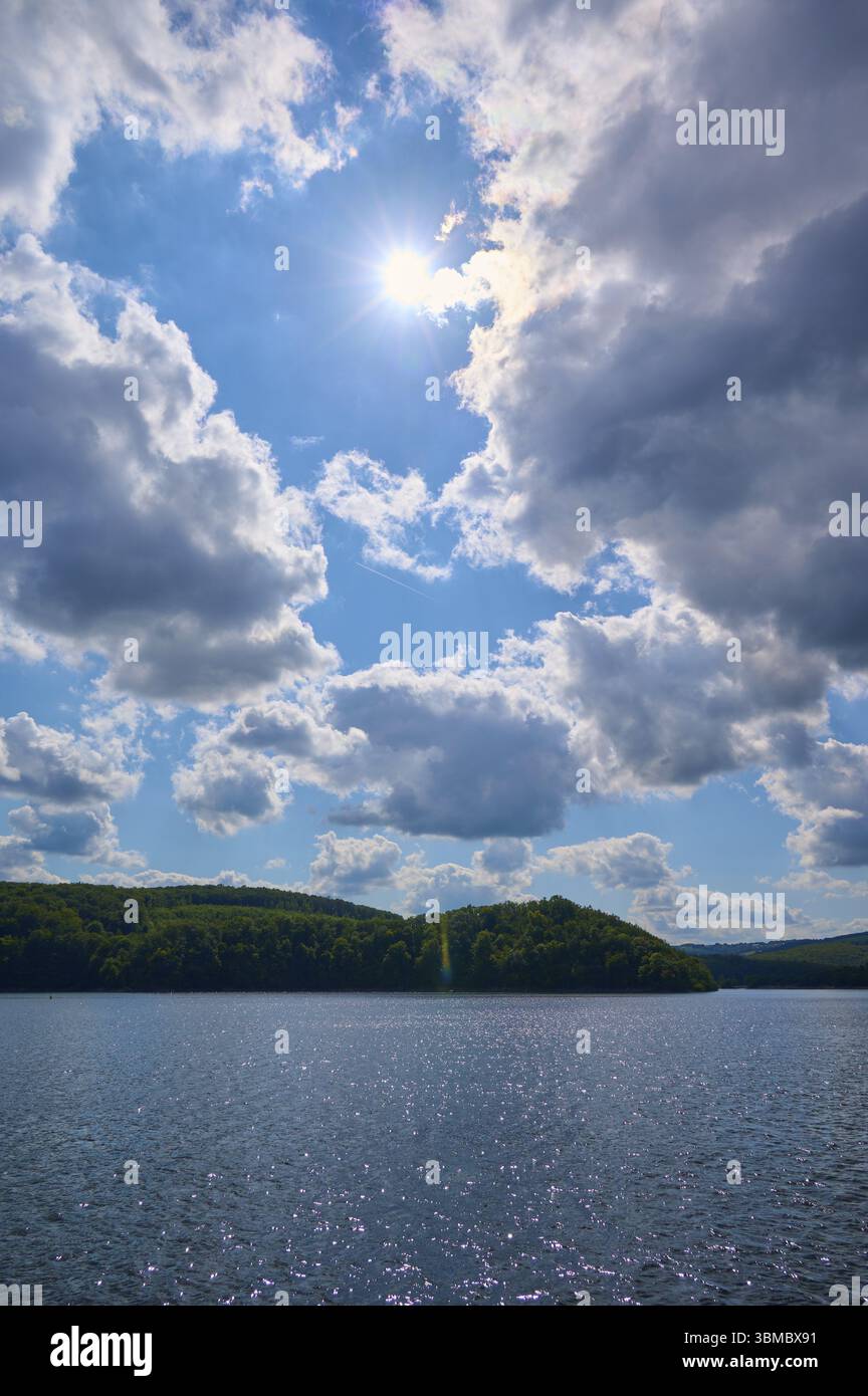 Un ciel ensoleillé au-dessus d'un lac calme avec des nuages éparpillés et des collines verdoyantes, été, Rursee, Rurtalsperre, Simmerath, parc national de l'Eifel, Rhénanie du Nord-Westphal Banque D'Images
