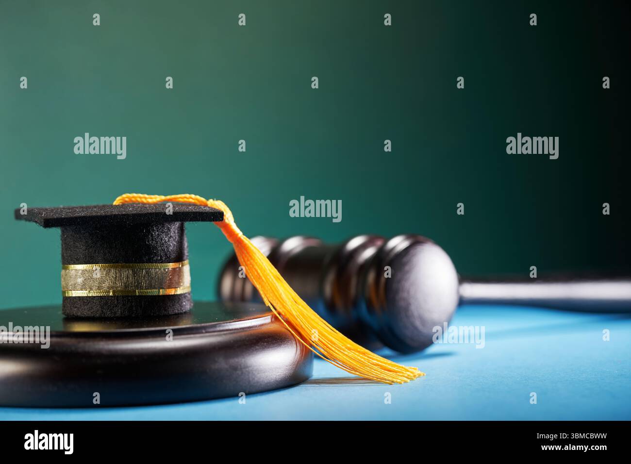 petit mortarboard sur maillet avec marteau sur fond bleu et vert Banque D'Images