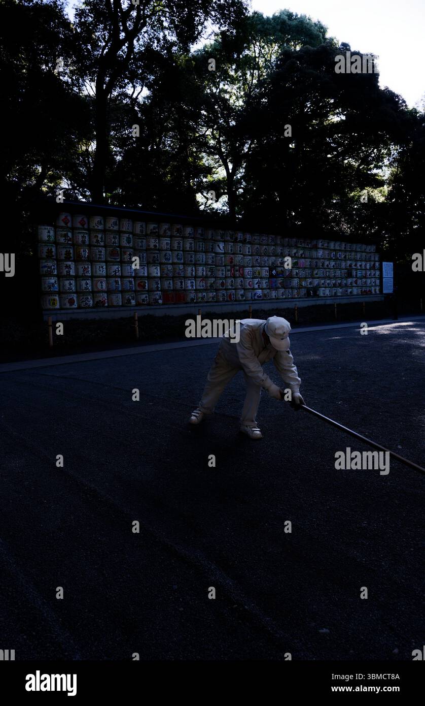 Travailleur ratissant soigneusement un chemin de gravier dans le parc Yoyogi Banque D'Images