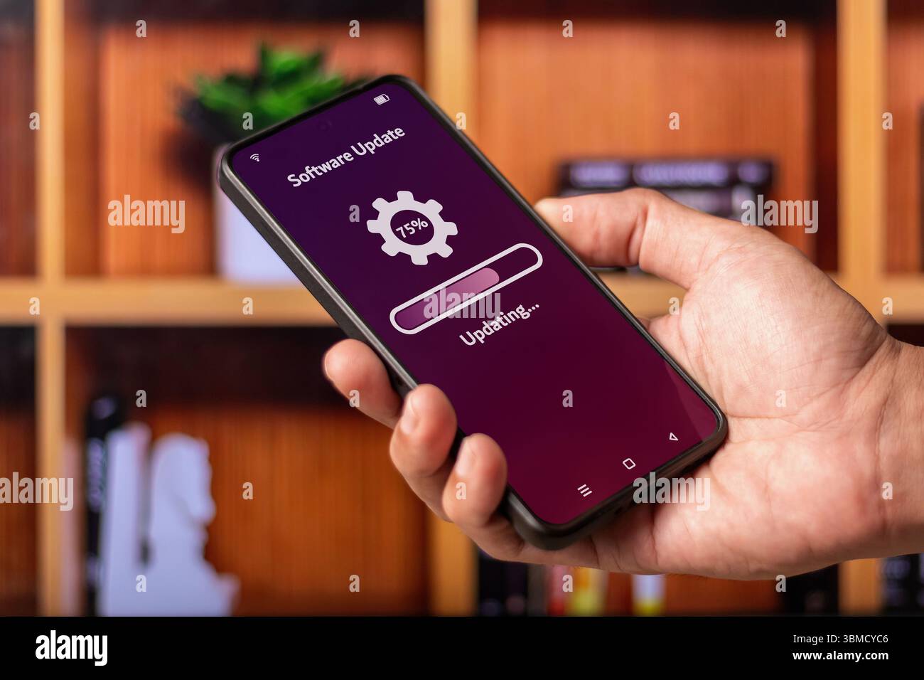 Main tenant un smartphone avec processus de mise à jour du système logiciel ou de l'application sur l'écran Banque D'Images